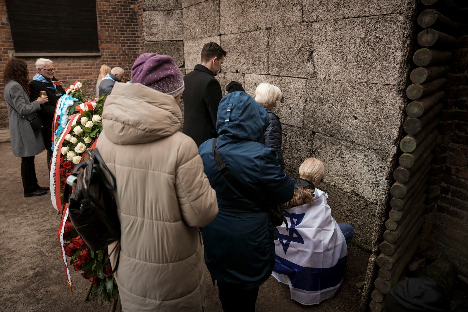 Survivors and relatives place candles near the Death Wall during a ceremony at the Auschwitz-Birkenau former Nazi German concentration and extermination camp, in Oswiecim, Poland, Monday, Jan. 27. 2025. (AP Photo/Oded Balilty)