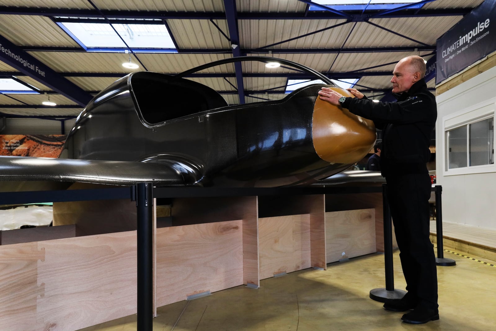 Swiss aviation pioneer Bertrand Piccard touches Climate Impulse, a plane powered by liquid hydrogen, at the press presentation of the project in a hangar in Les Sables d'Olonne, France on Thursday, Feb. 13, 2025.(AP Photo/Yohan Bonnet)