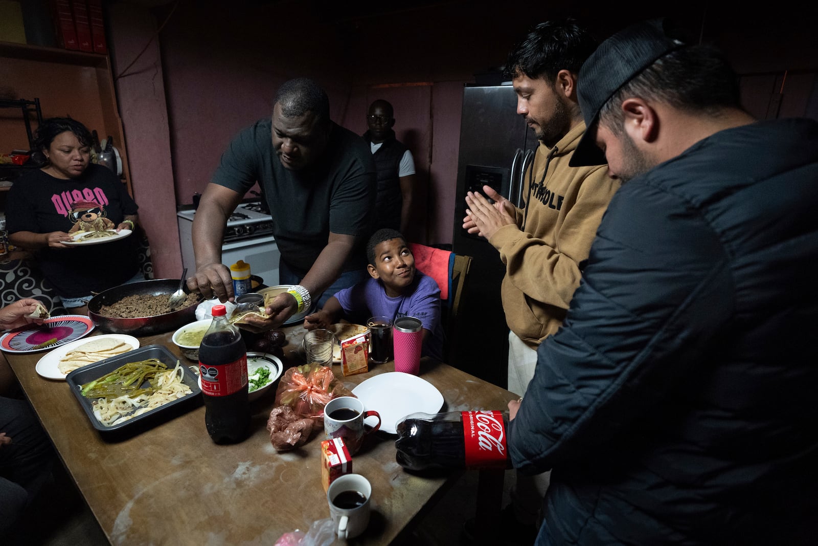 Cuban migrant Dayron Garcia, above center, fills a taco as he eats with other migrants staying at Martha Rosales' home while waiting an appointment to apply for asylum in the United States through the CBP One app Wednesday, Aug. 28, 2024, in Tijuana, Mexico. (AP Photo/Gregory Bull)