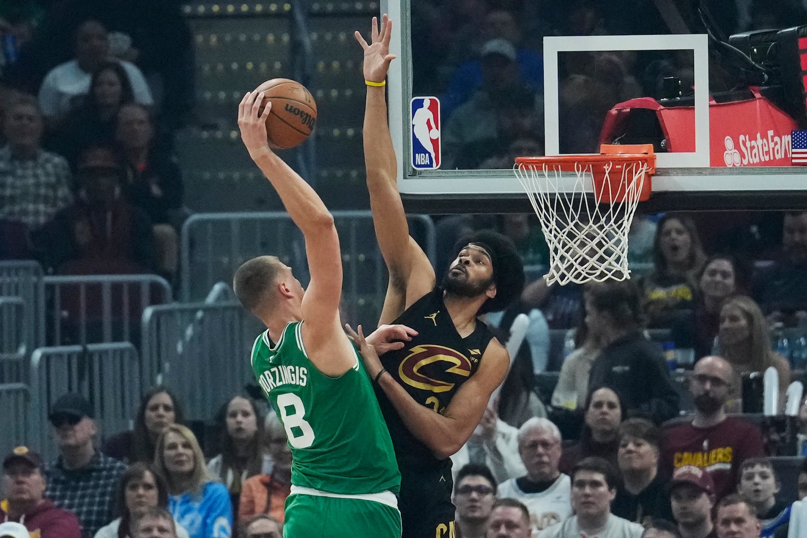 Boston Celtics center Kristaps Porzingis (8) goes up for a shot as Cleveland Cavaliers center Jarrett Allen, right, defends in the first half of an NBA basketball game, Tuesday, Feb. 4, 2025, in Cleveland. (AP Photo/Sue Ogrocki)