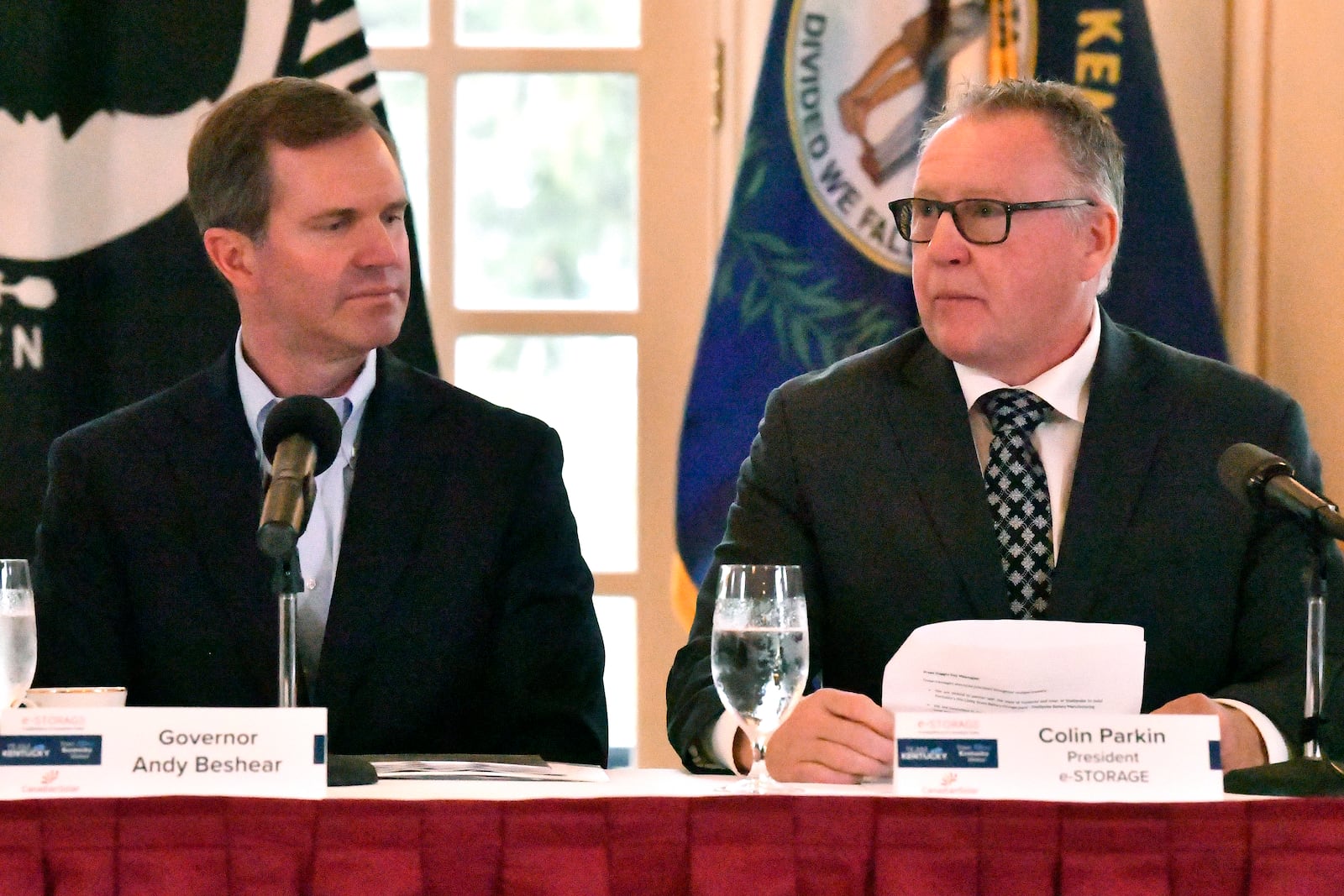 Kentucky Governor Andy Beshear listens as Colin Parkin, President of e-Storage, speaks during the announcement of a $712 million project in Shelbyville, Ky., creating 1,572 skilled, high-tech jobs at the Governor's Mansion in Frankfort, Ky., Friday, Nov. 15, 2024. (AP Photo/Timothy D. Easley)