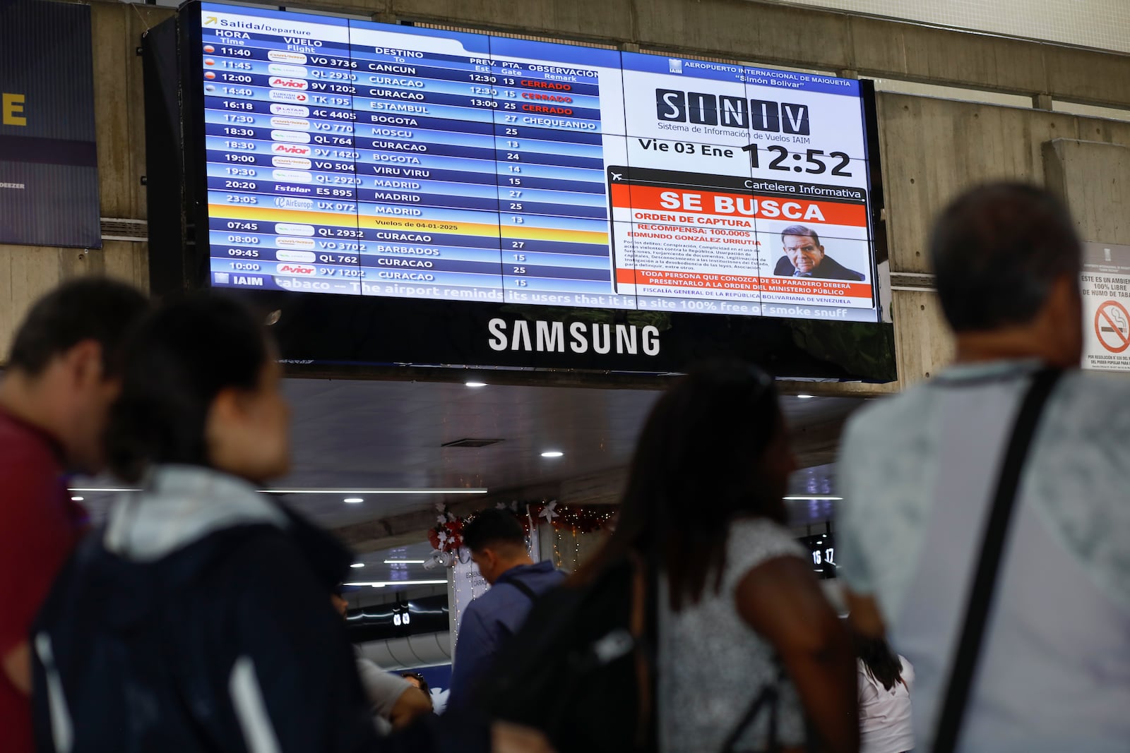 A wanted sign of Venezuelan opposition leader Edmundo Gonzalez is displayed on the list of departure flights at the Simon Bolivar International Airport in Maiquetia, near Caracas, Venezuela, Friday, Jan. 3, 2025. (AP Photo/Cristian Hernandez)