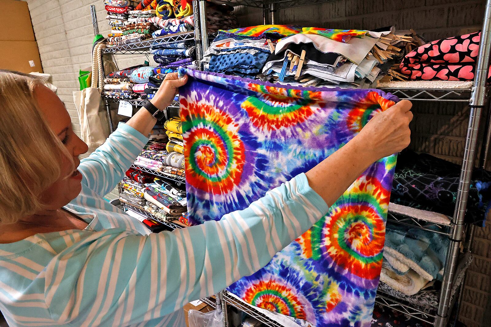 Lynette Evans shows some of the weighted blankets she makes for children on the autistic spectrum, Wednesday, April 12, 2023 in her basement workshop. BILL LACKEY/STAFF