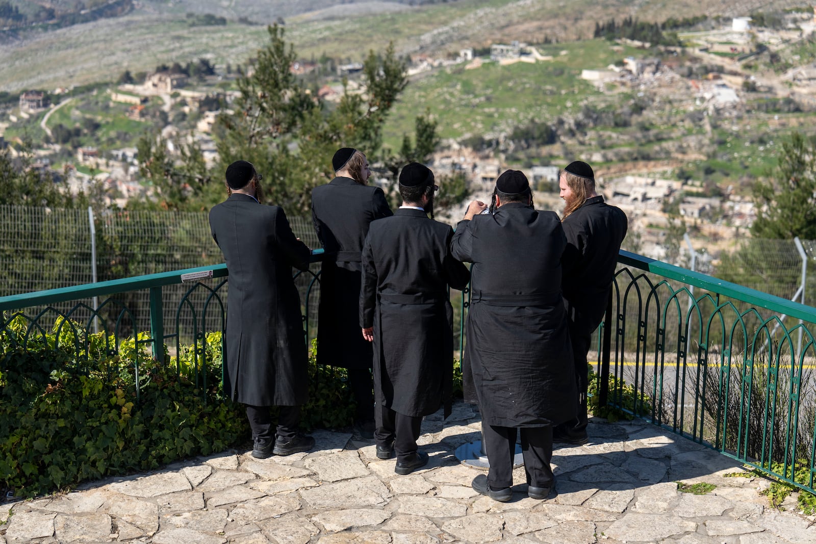 Ultra-Orthodox Jewish men look from Kibbutz Misgav Am in northern Israel at the village of Odaisseh in Southern Lebanon after Israeli forces withdrew from border villages , Tuesday, Feb. 18, 2025. (AP Photo/Ariel Schalit)