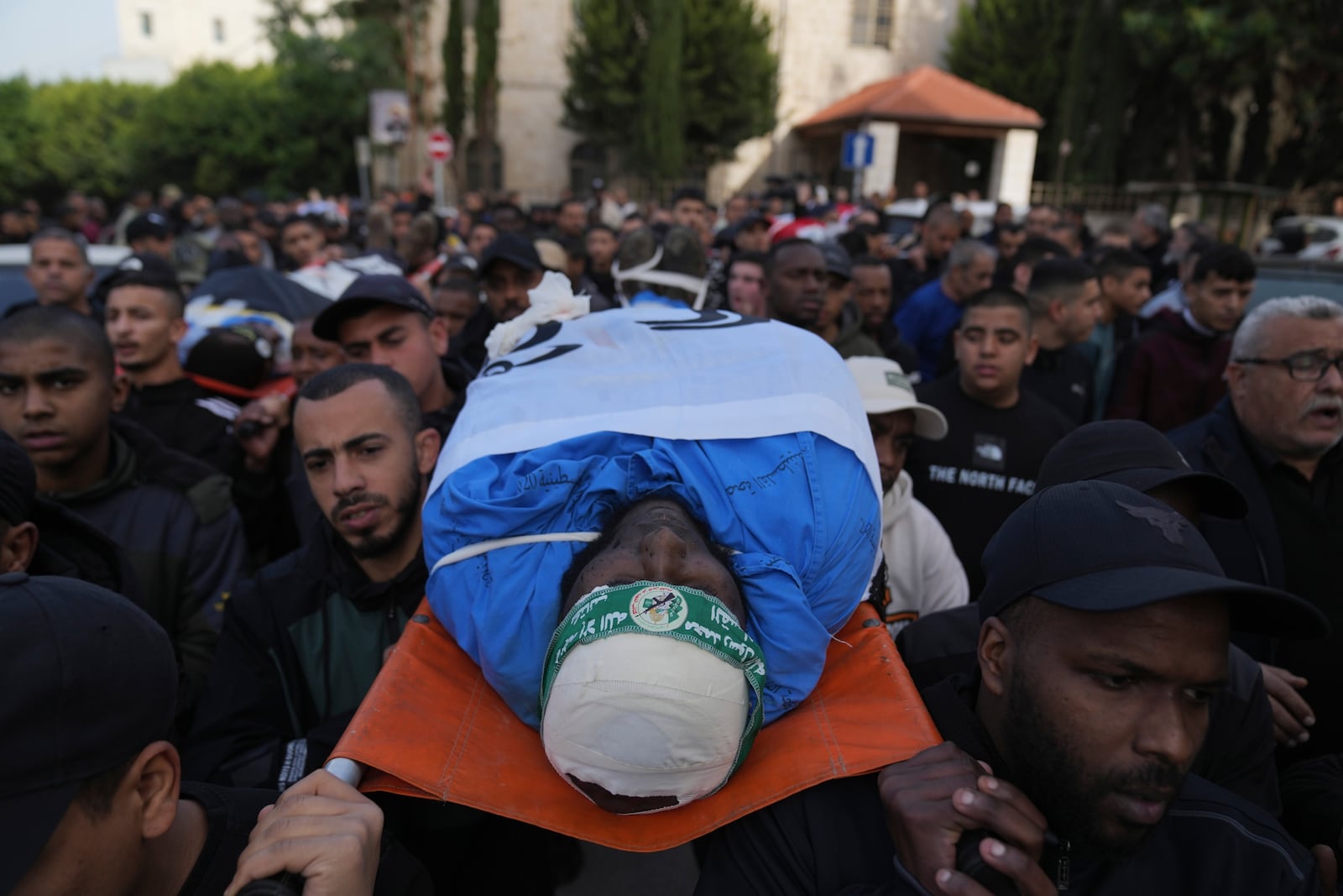 Mourners carry the bodies of eight killed Palestinians, some are wrapped with the Islamic Jihad flag, during their funeral following the withdrawal of the Israeli army, in the West Bank city of Tulkarem, Thursday, Dec. 26, 2024. (AP Photo/Nasser Nasser)