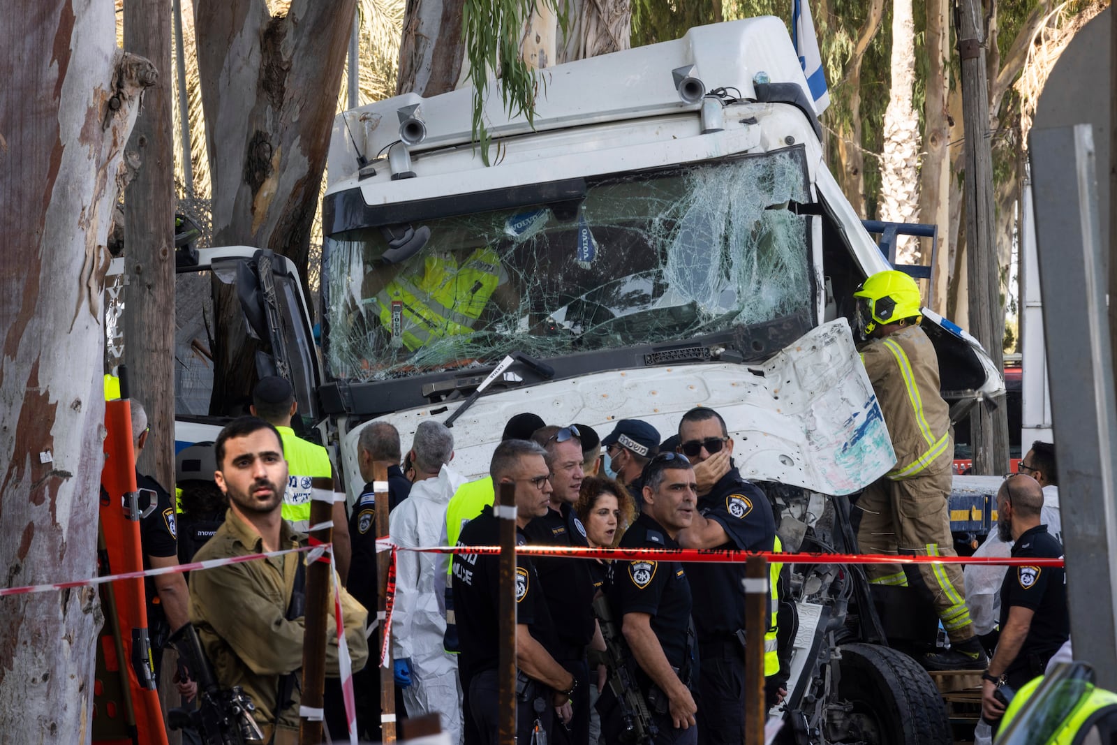 Israeli police and rescue services inspect the site where a truck driver rammed into a bus stop near an army base, wounding dozens of people, according to Israel's Magen David Adom rescue service in Ramat Hasharon, Israel, Sunday, Oct. 27, 2024. (AP Photo/Oded Balilty)