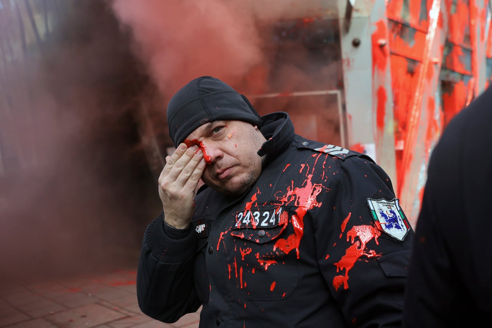 A policeman holds his eye during clashes with nationalist protesters who demanded the government scrap plans to take the country into the eurozone, in front of the Sofia office of the European Commission, Saturday, Feb. 22, 2025. (AP Photo/Valentina Petrova)