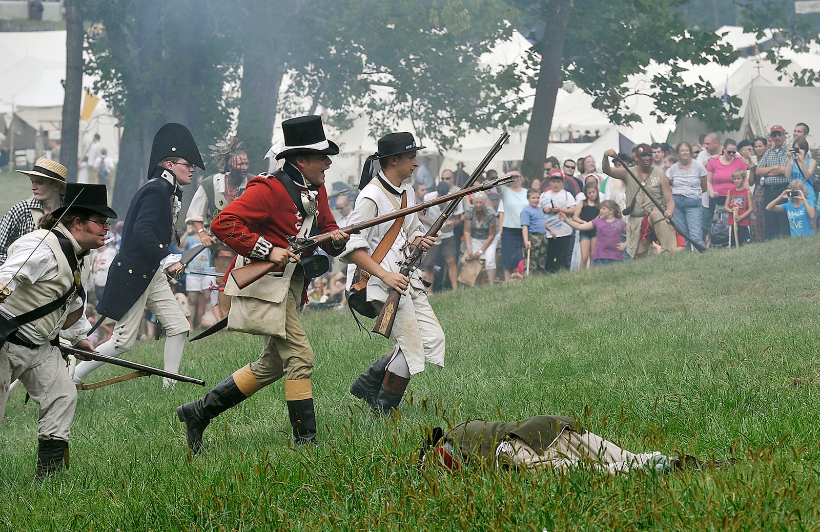 Spectators watch as reenactors charge across the battlefield during a mock battle Saturday at the Fair at New Boston at George Rogers Clark Park. The two day event, which continues Sunday, brings the early 19th century alive with reenactors and performers in an authentic settlement with shops, food and encampments. Bill Lackey/Staff