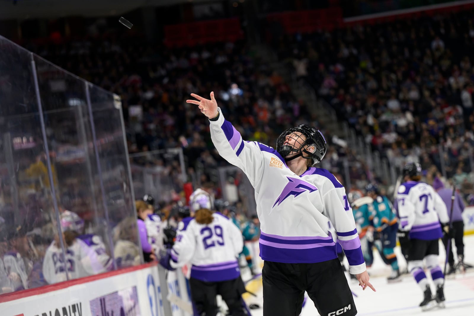 Minnesota forward Grace Zumwinkle tosses a puck to a fan after it was announced that the game brought the total fan attendance to over one million during the first period of a PWHL game between the New York Sirens and the Minnesota Frost, at Little Caesars Arena, in Detroit, Sunday, March 16, 2025. (David Guralnick/Detroit News via AP)