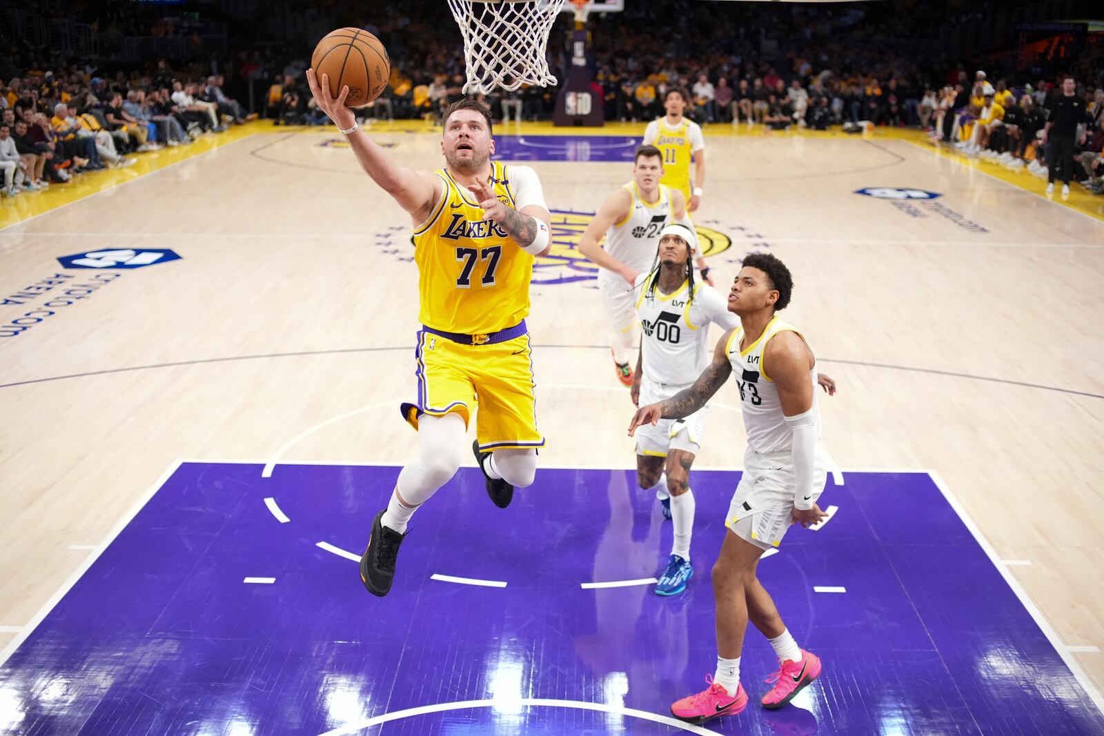 Los Angeles Lakers guard Luka Doncic (77) shoots as Utah Jazz guard Jordan Clarkson (00) and guard Johnny Juzang defend during the first half of an NBA basketball game, Monday, Feb. 10, 2025, in Los Angeles. (AP Photo/Mark J. Terrill)