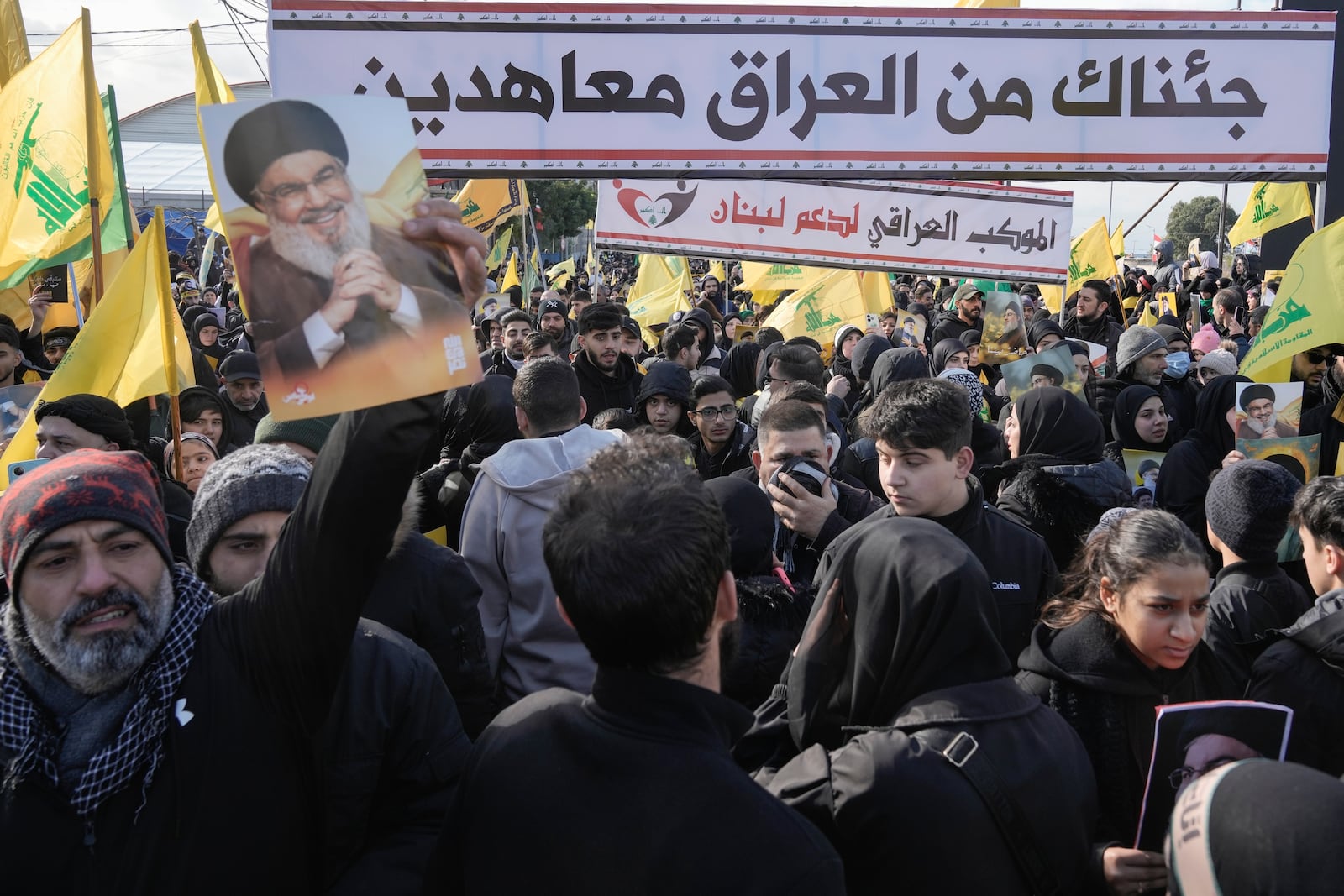 Mourners from Iraq hold pictures of Hezbollah's former leader Hassan Nasrallah as they gather along a highway to attend his funeral procession in Beirut, Lebanon, Sunday Feb. 23, 2025. (AP Photo/Bilal Hussein)