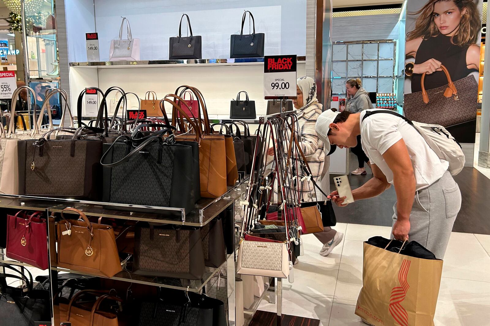 A shopper looks at handbags at Macy's department store on Sunday, Nov. 24, 2024, in New York. (AP Photo/Anne D'Innocenzio)