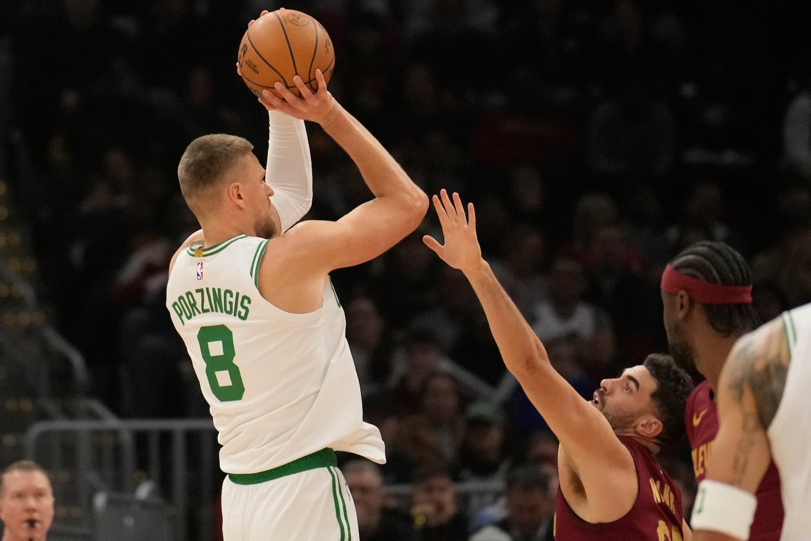 Boston Celtics center Kristaps Porzingis (8) shoots over Cleveland Cavaliers forward Georges Niang, right, in the first half of an NBA basketball game, Sunday, Dec. 1, 2024, in Cleveland. (AP Photo/Sue Ogrocki)