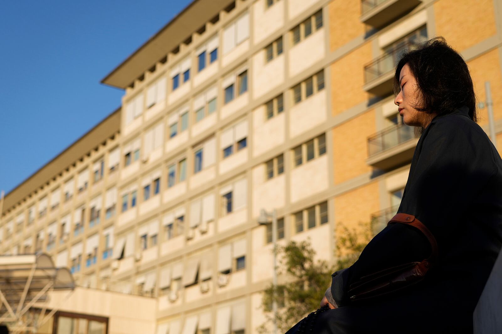 A woman prays outside the Agostino Gemelli Polyclinic where Pope Francis is hospitalized in Rome, Tuesday, March 4, 2025. (AP Photo/Gregorio Borgia)