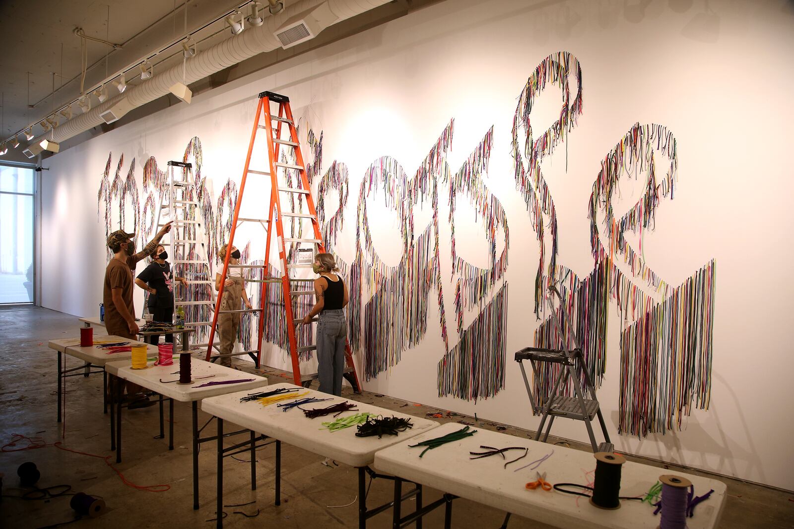 Volunteers hang thousands of shoelaces at The Contemporary Dayton Wednesday to create We The People, a 50-foot-wide wall installation designed by artist Nari Ward. The installation pairs humble of materials (shoelaces) with one of the country’s most lofty and enduring ideas—the U.S. Constitution, according to a release. The artwork will be on display through Nov. 30. The Co has also partnered with the League of Women Voters of the Greater Dayton Area to transform a portion of the gallery into a voter registration center.  LISA POWELL / STAFF