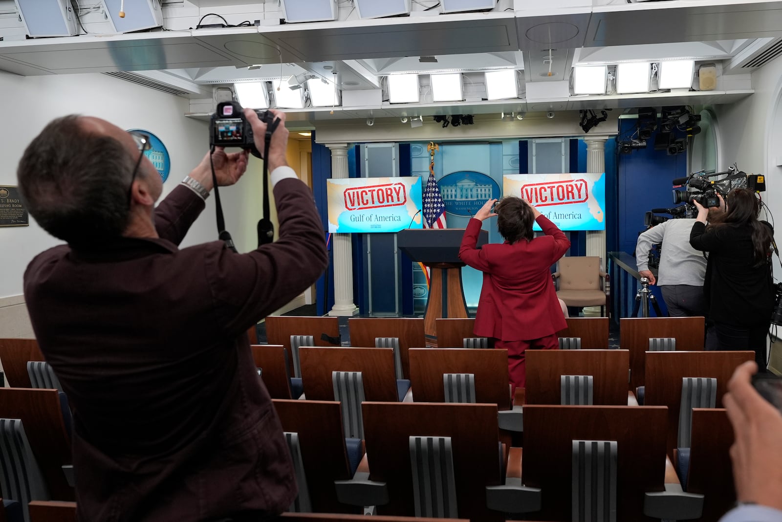 People take photos of monitors behind the podium in the James Brady Press Briefing Room at the White House, Monday, Feb. 24, 2025, in Washington. (AP Photo/Alex Brandon)