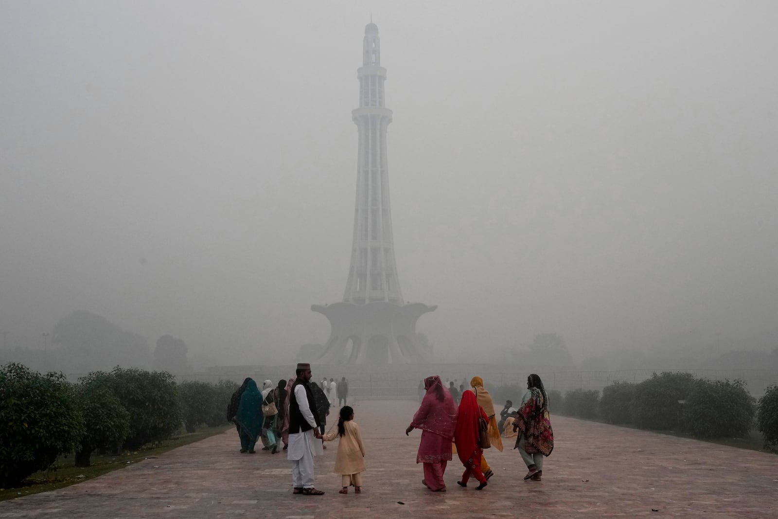 Families arrive at Minar-e-Pakistan or Pakistan monument as smog envelops the area of Lahore, Pakistan, Friday, Nov. 8, 2024. (AP Photo/K.M. Chaudary)