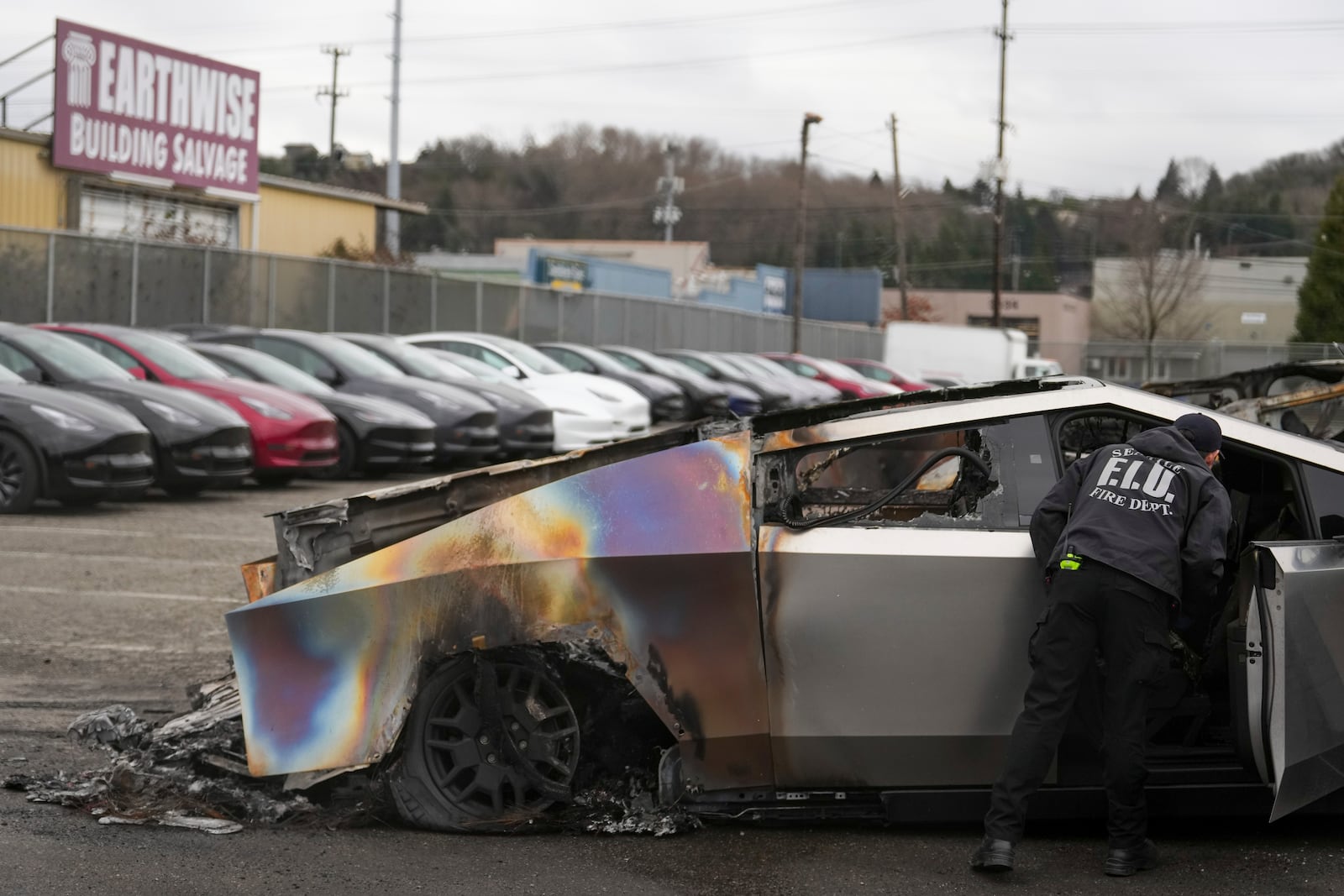 A member of the Seattle Fire Department inspects a burned Tesla Cybertruck at a Tesla lot in Seattle, Monday, March 10, 2025. (AP Photo/Lindsey Wasson)