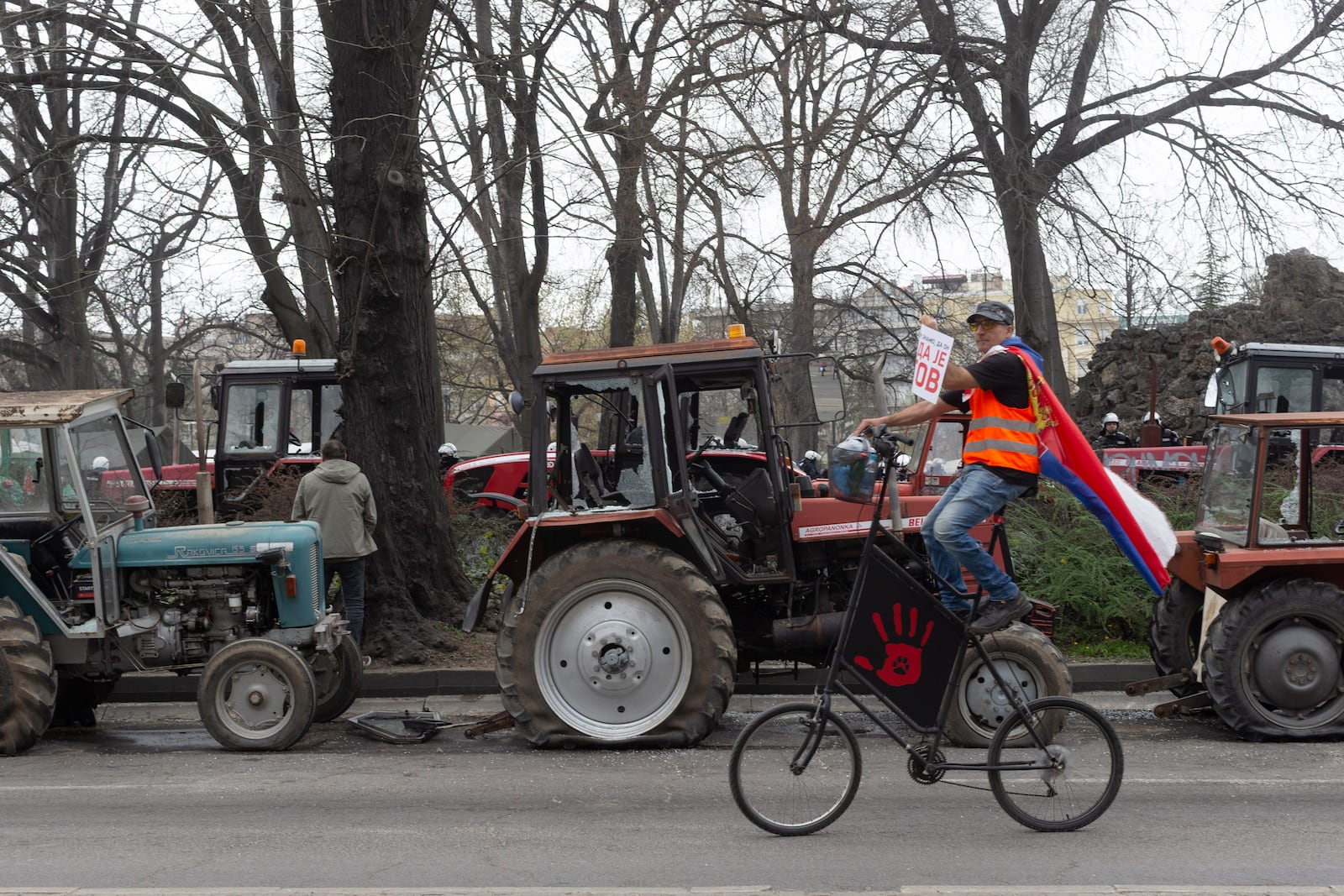 A protester rides his bicycle past damaged tractors parked by supporters of the Serbian president during a major anti-corruption rally led by university students in Belgrade, Serbia, Saturday, March 15, 2025. (AP Photo/Marko Drobnjakovic)