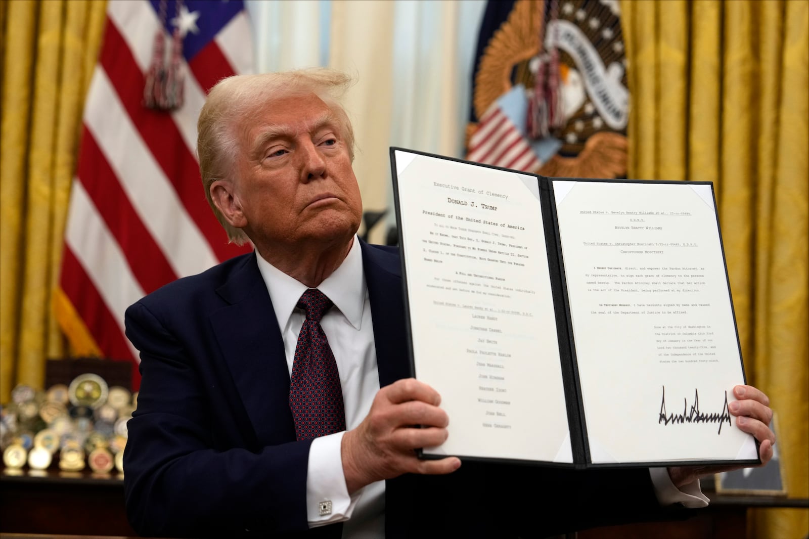 President Donald Trump holding up a order for clemency for anti-abortion protesters as he signs executive orders in the Oval Office of the White House, Thursday, Jan. 23, 2025, in Washington. (AP Photo/Ben Curtis)