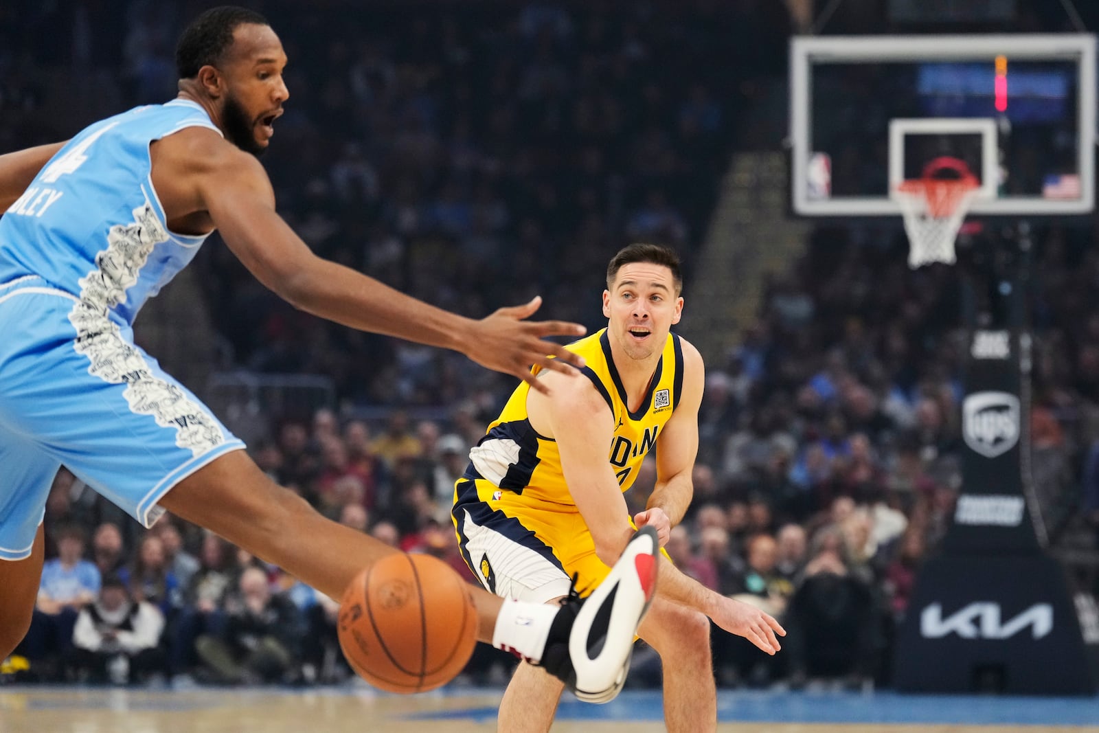 Indiana Pacers guard T.J. McConnell, right, passes in front of Cleveland Cavaliers forward Evan Mobley, left, in the first half of an NBA basketball game, Sunday, Jan. 12, 2025, in Cleveland. (AP Photo/Sue Ogrocki)