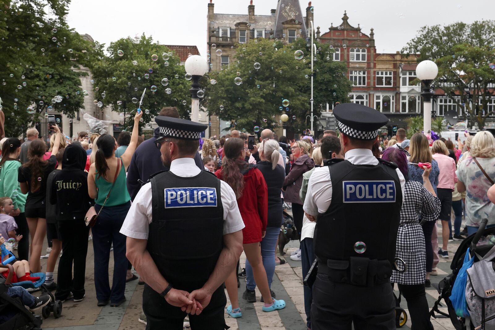 FILE - Police officers watch members of the public outside the Town Hall in Southport, England, Monday, Aug. 5, 2024 after three young girls were killed in a knife attack at a Taylor Swift-themed holiday club the week before. (AP Photo/Darren Staples, File)