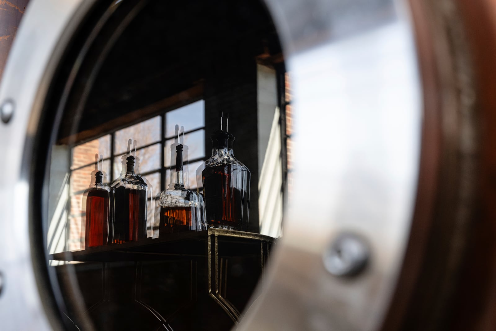 Bottles of The Bard product are seen in the reflection of a new column still that is not yet in use at The Bard Distillery in Graham, Ky., Sunday, March 9, 2025. (AP Photo/Jon Cherry)