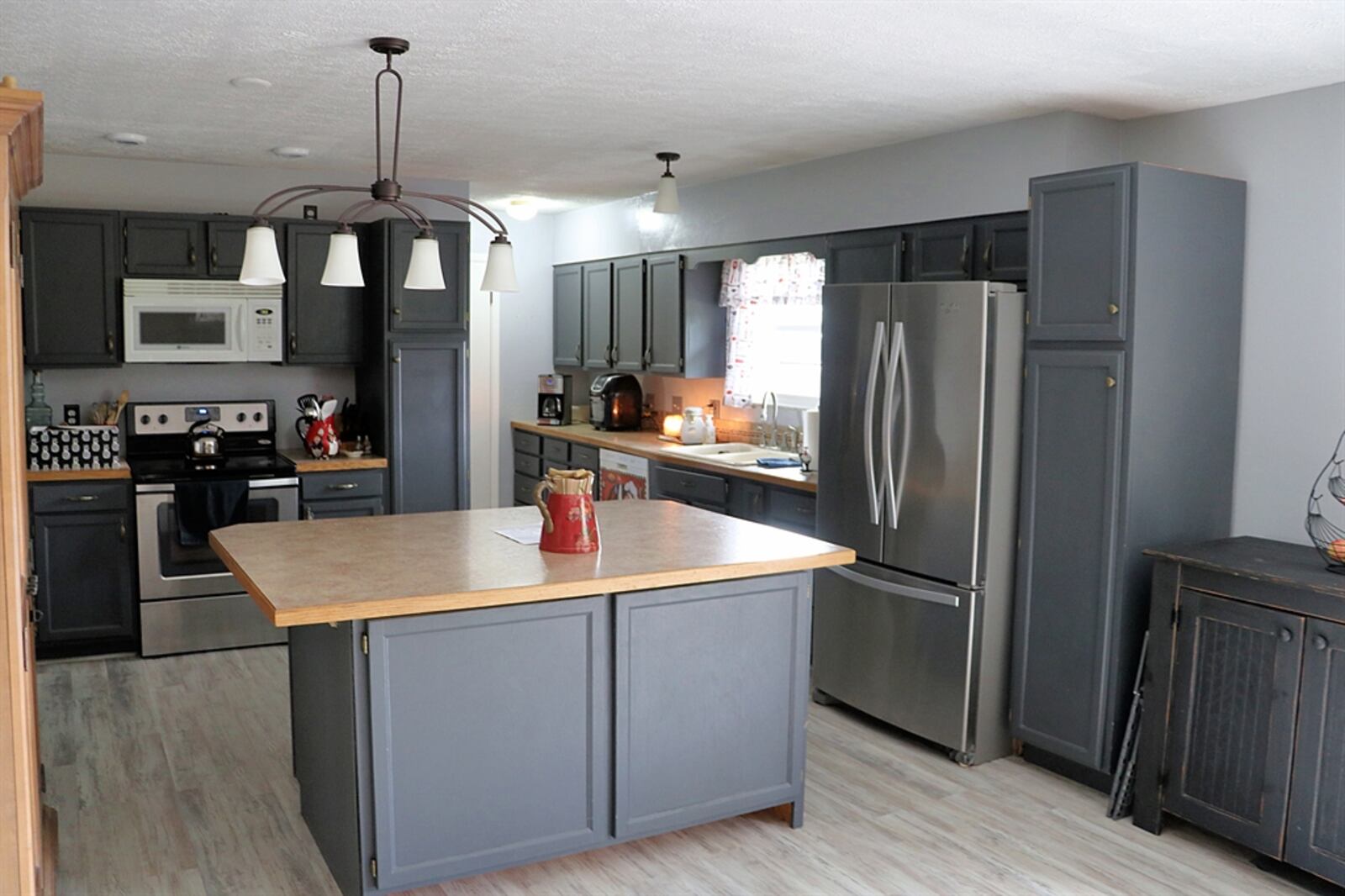 In the kitchen, an oversized island provides plenty of preparation space and storage options. Additional cabinetry offers three pantries and wraparound appliances that include a range, dishwasher, microwave and refrigerator.