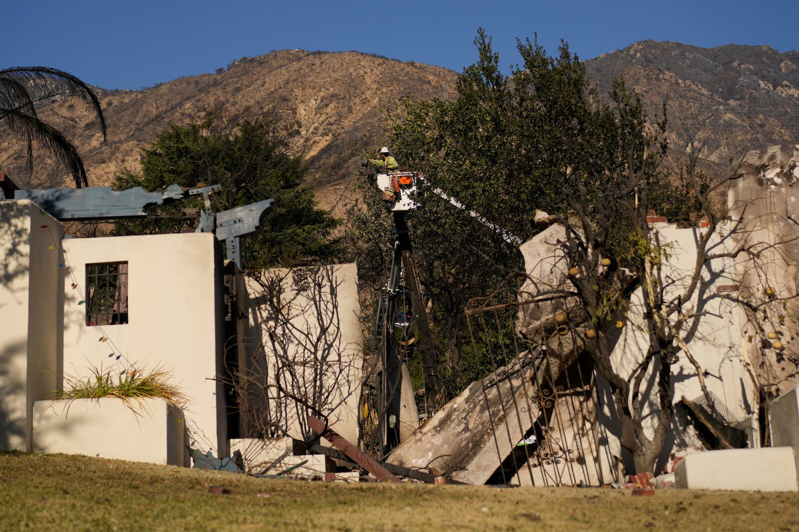 A worker services a utility pole in the aftermath of the Eaton Fire on Monday, Jan. 13, 2025, in Altadena, Calif. (AP Photo/Carolyn Kaster)