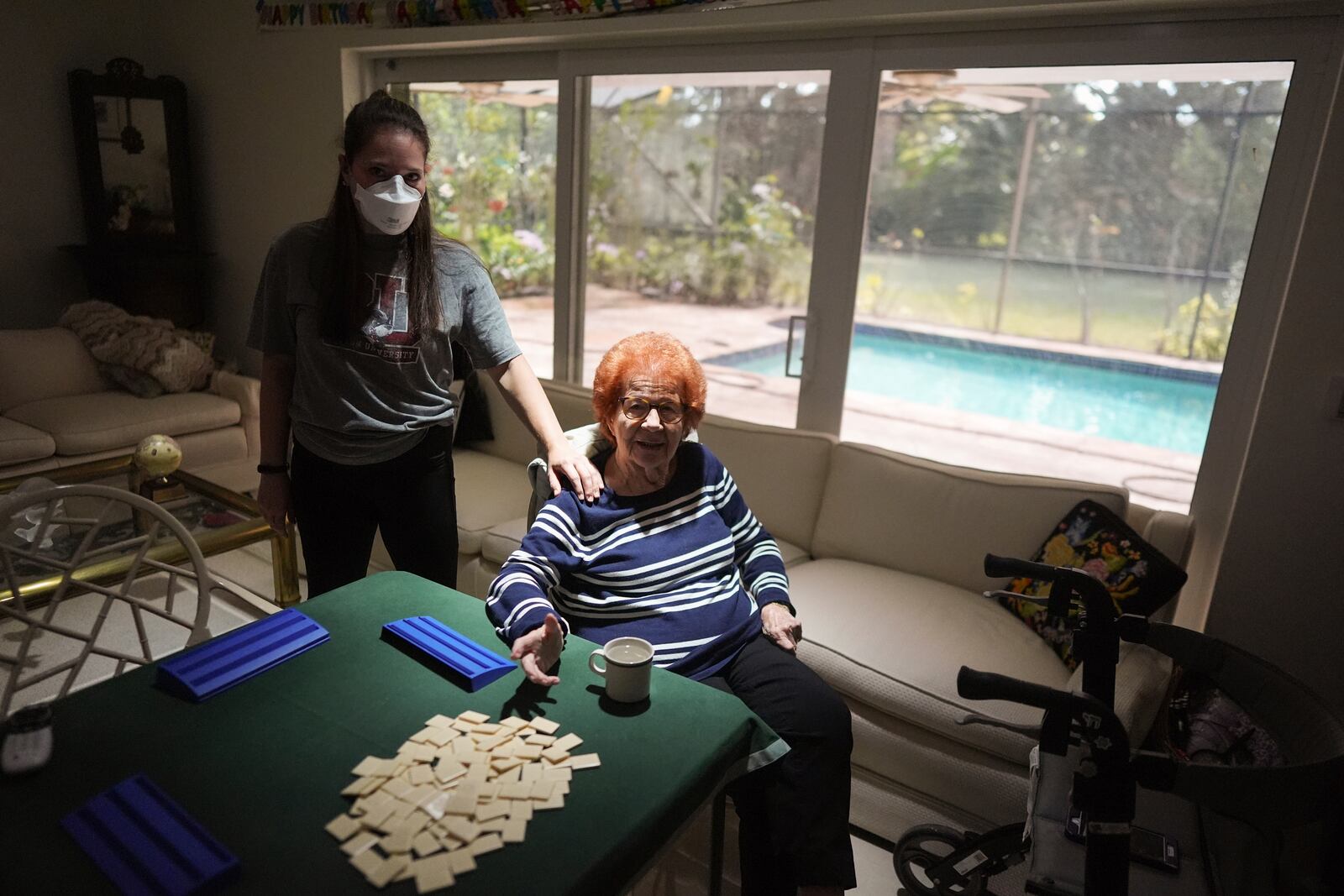 Kira Levin, 29, left, stands with her 98-year-old grandmother Jeanette Levin, in their living room in Pinecrest, Fla., Monday, Dec. 16, 2024. Kira, who moved back in with her parents when COVID hit as she was finishing her masters degree, has become a primary caregiver to her grandmother while also working from home. (AP Photo/Rebecca Blackwell)