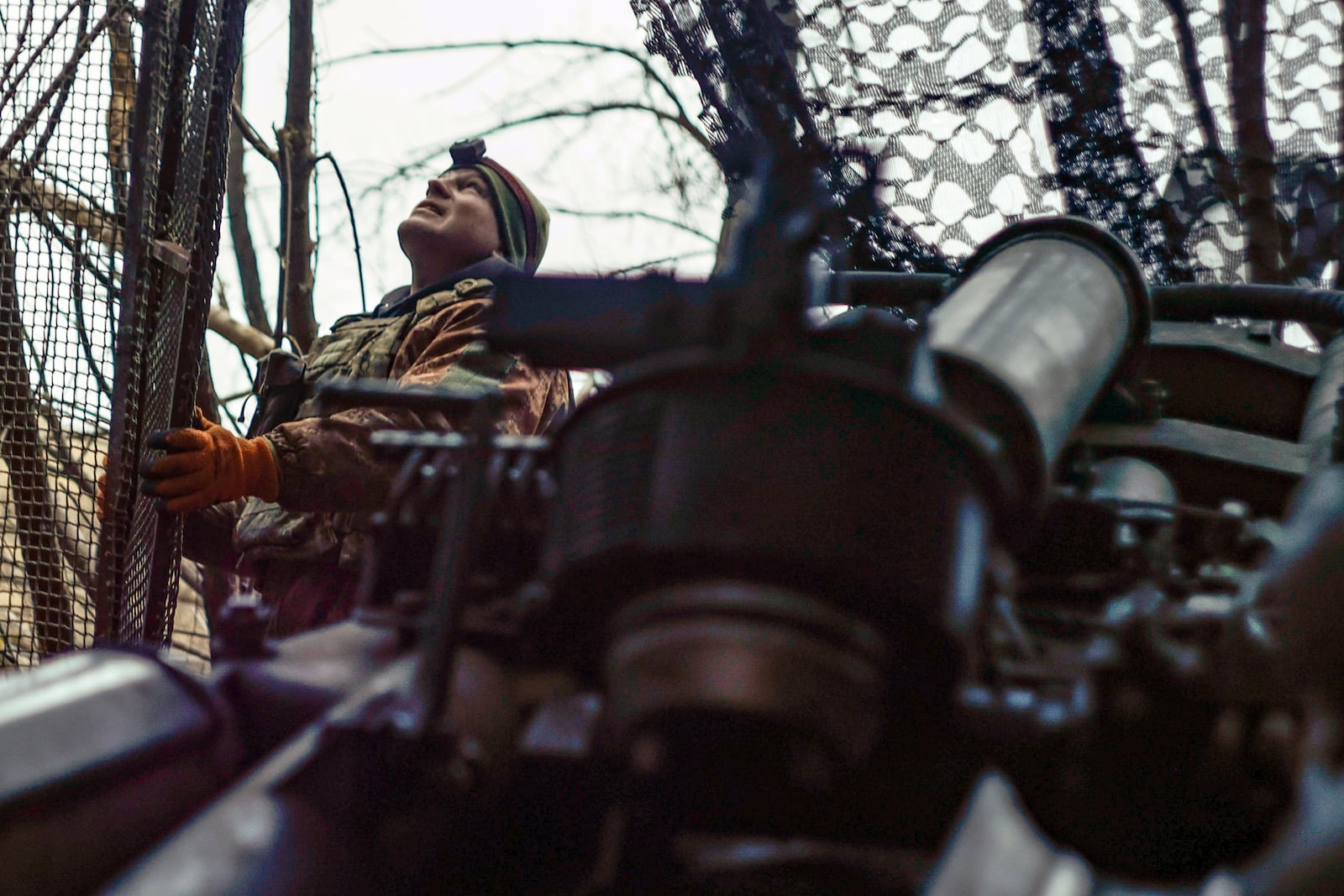 A Ukrainian soldier looks at the sky searching for Russian FPV drones as he gets ready to fire a M777 howitzer towards Russian positions at the frontline near Donetsk, Ukraine, Monday, March 3, 2025. (AP Photo/Roman Chop)