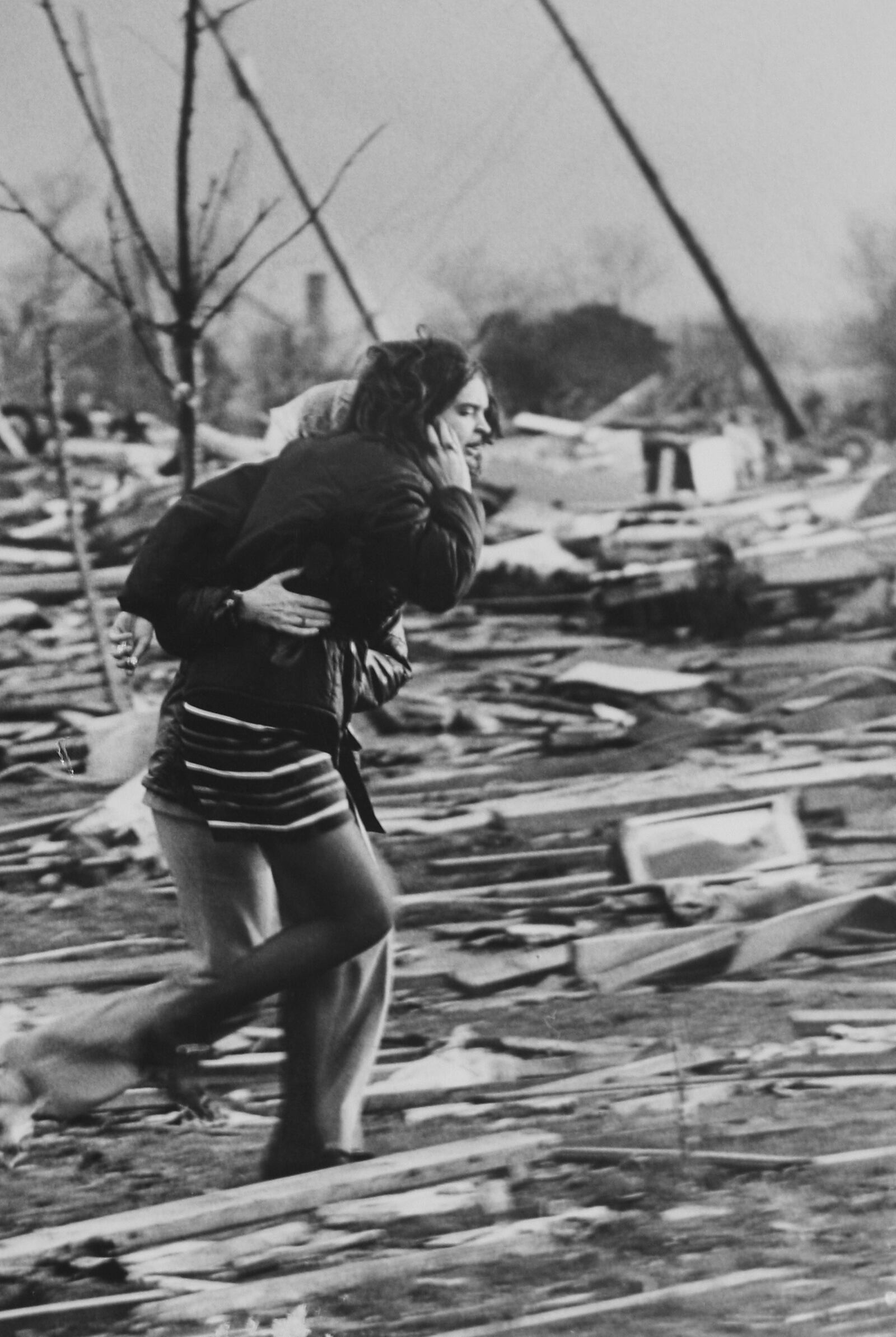 A mother and daughter run throuhg the rubble that had been their home in the Arrowhead sub division of Xenia Ohio. A second tornado warning had just been given and many of the survivors just ran in panic.Photo by Ed Roberts