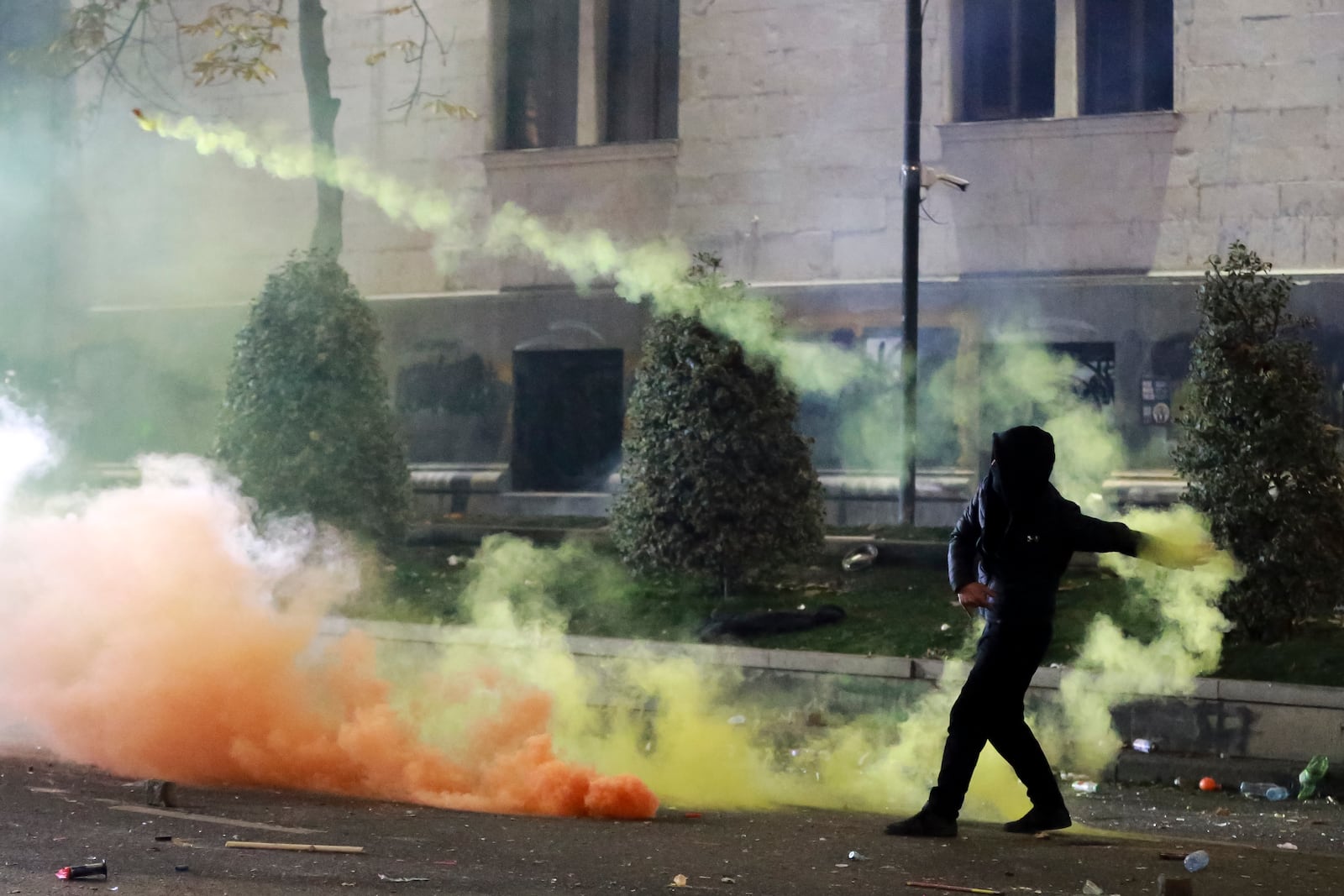 A demonstrator throws a petard against police who blocked a street to prevent protesters rallying against the governments' decision to suspend negotiations on joining the European Union for four years, outside the parliament's building in Tbilisi, Georgia, early Saturday, Nov. 30, 2024. (AP Photo/Zurab Tsertsvadze)