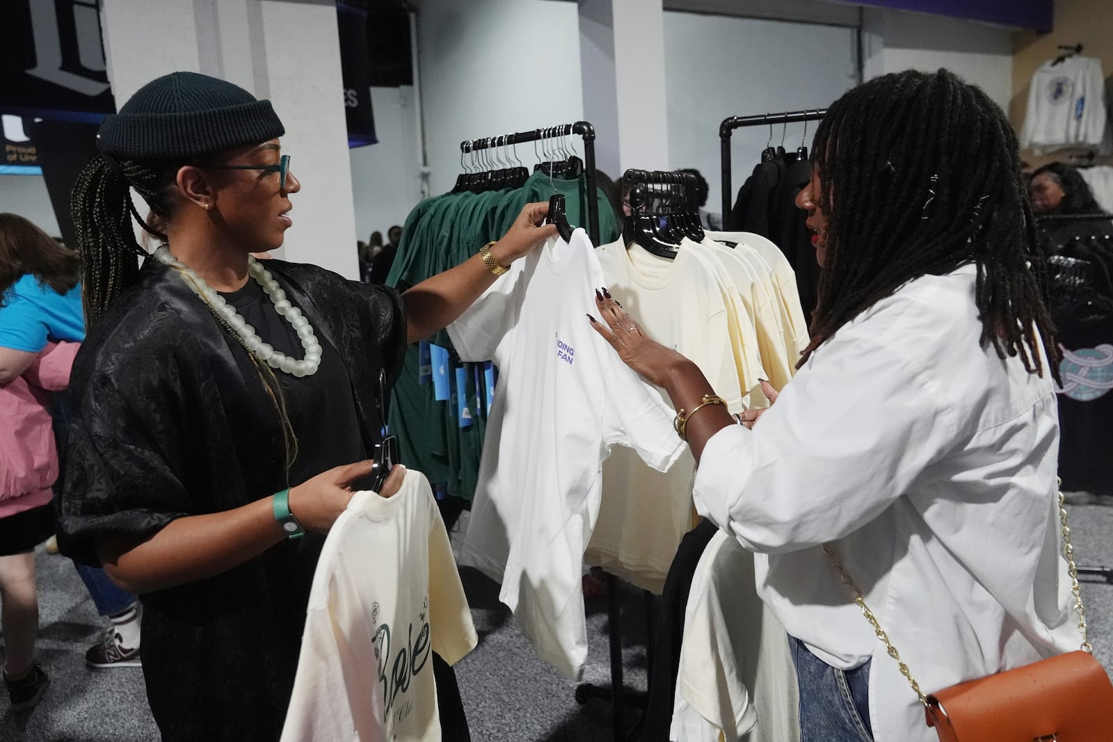 Rebecca Bernard, left and Danielle Moodie, look at merchandise before the Unrivaled 3-on-3 women's basketball game between Lunar Owls and Mist, Friday, Jan. 17, 2025, in Medley, Fla. (AP Photo/Marta Lavandier)