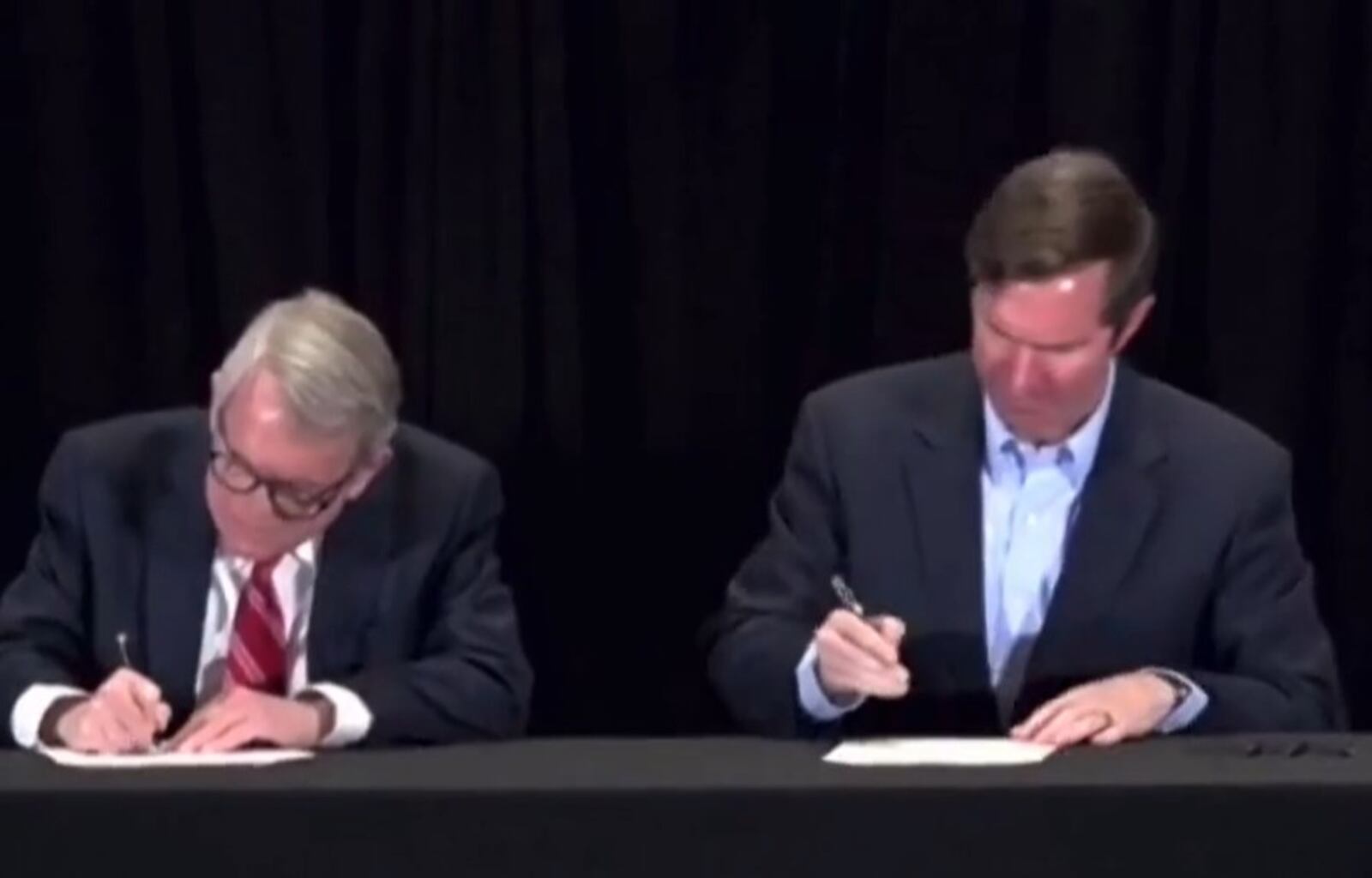 Ohio Gov. Mike DeWine and Ky. Gov. Andy beshear sign a memorandum that each state will apply for an equal share of federal money to improve the Brent Spence Bridge. The signing and announcement took place in Kentucky Monday, Feb. 28, 2022. CONTRIBUTED