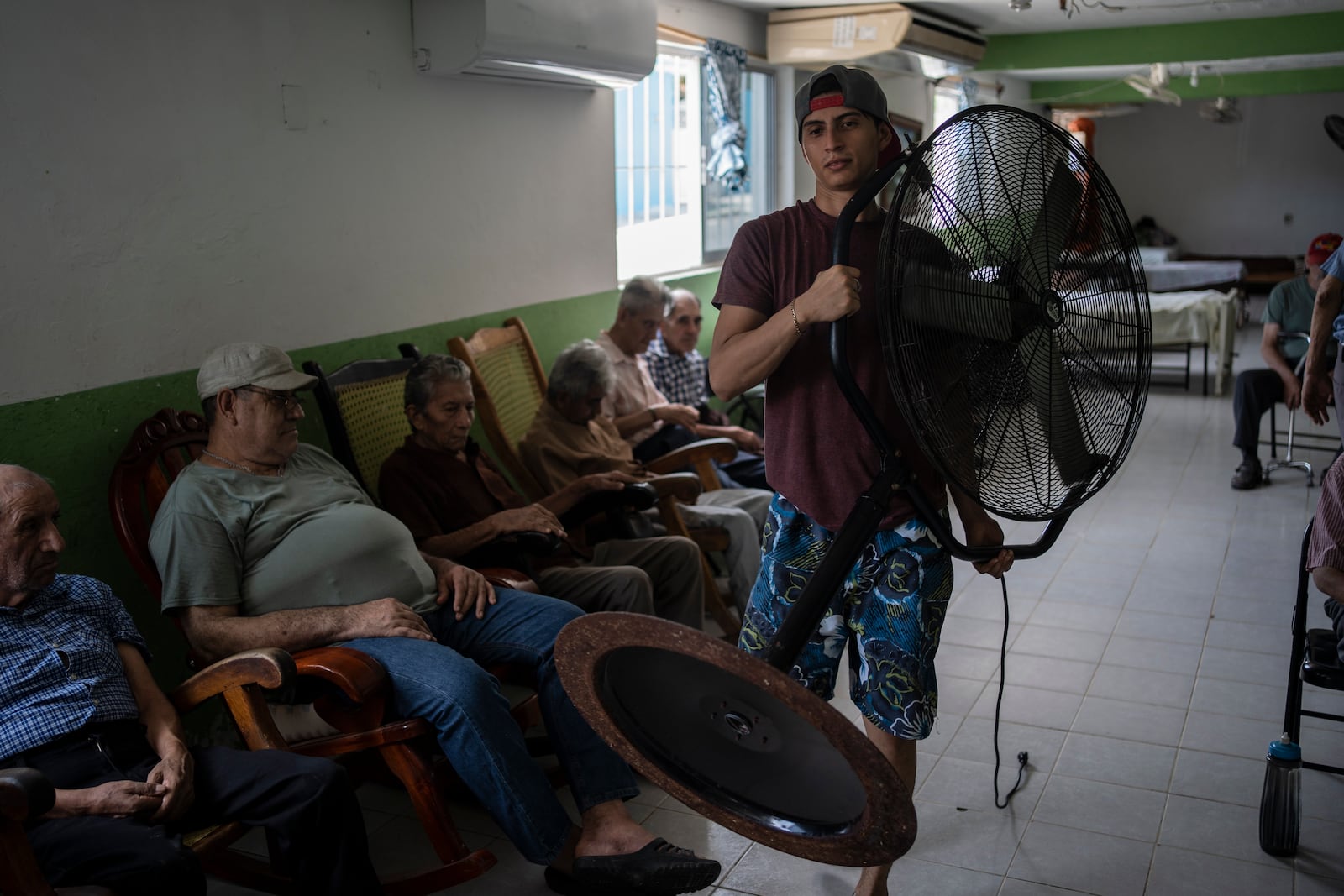 FILE - Humanitarian worker Roger Duvan Lagunes carries a fan into the Cogra, an elderly shelter, in Veracruz, Mexico, on June 16, 2024. (AP Photo/Felix Marquez, File)