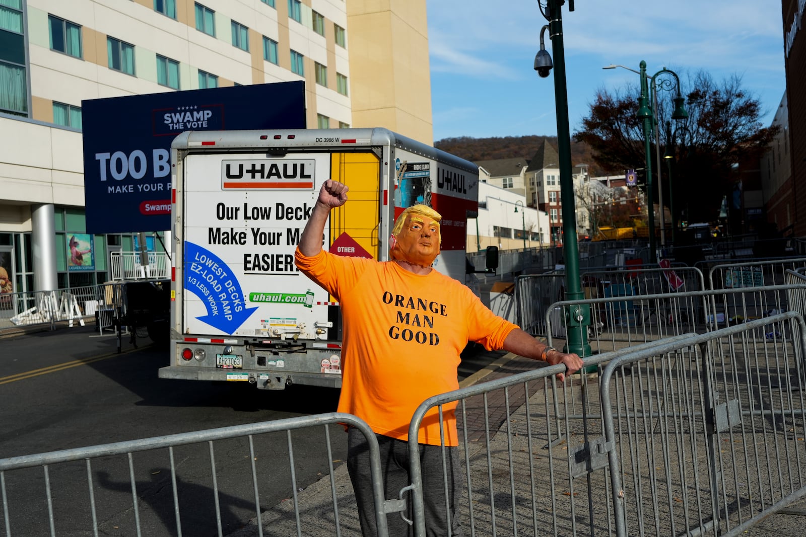 A Donald Trump supporter wearing a mask of the presidential candidate pumps his fist outside a Trump rally in Reading, Pa., Monday, Nov. 4, 2024. (AP Photo/Luis Andres Henao)