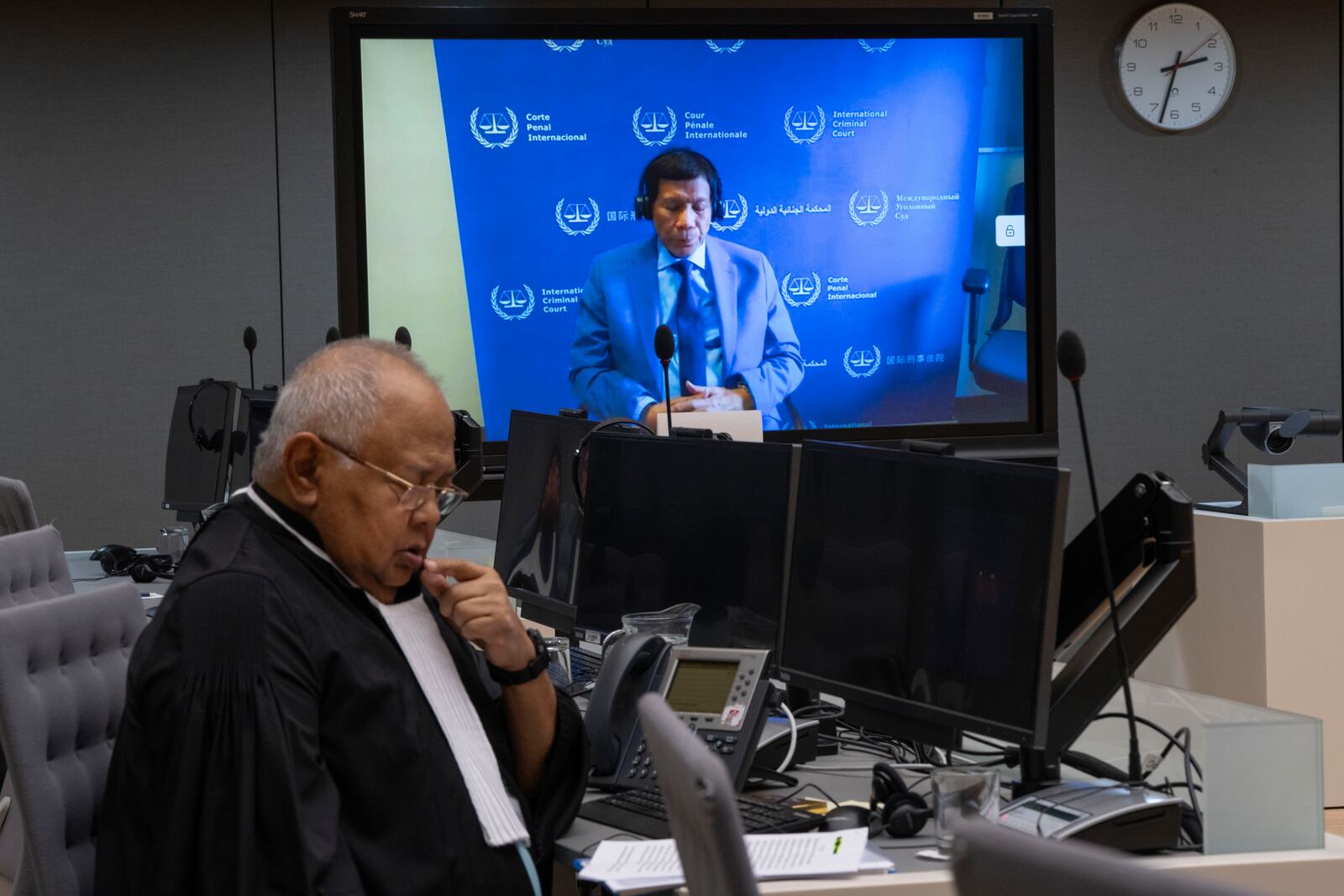 Former Philippine President Rodrigo Duterte is seen on a screen in the courtroom of the International Criminal Court (ICC) with his lawyer Salvador Medialdea seated left, in The Hague, Netherlands, Friday, March 14, 2025. (AP Photo/Peter Dejong, Pool)