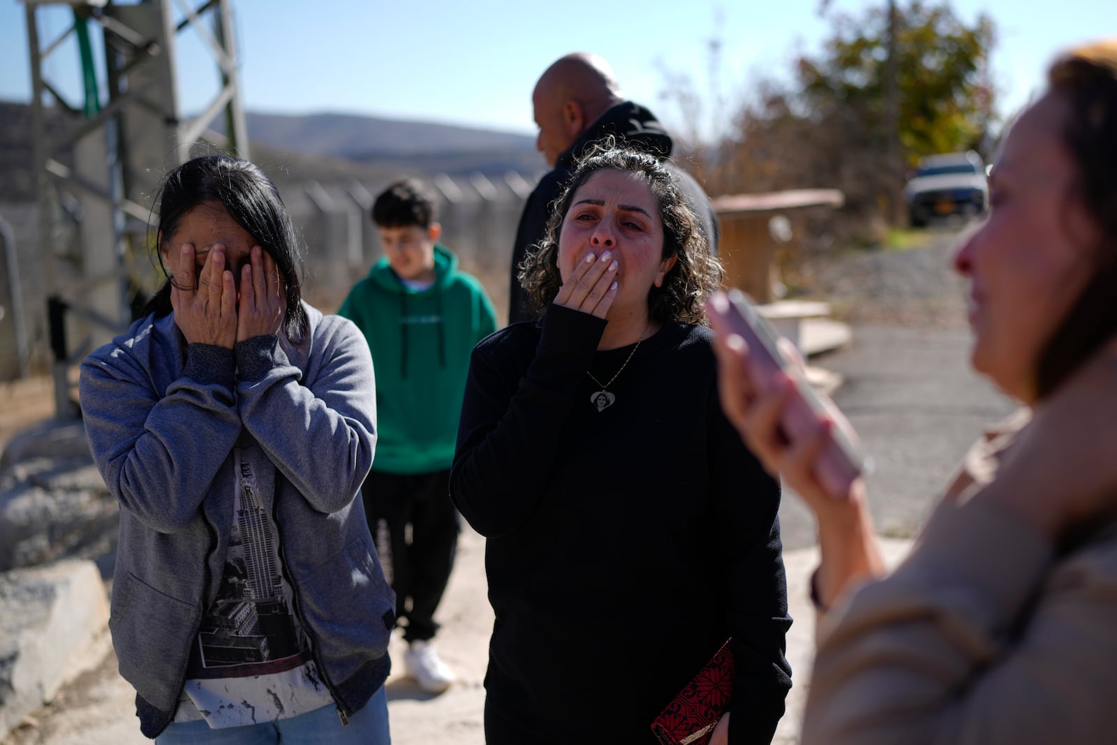 Safadi sisters Soha, left, and Salma, cry after speaking by phone with their sister, Sawsan, who is inside the buffer zone near the "Alpha Line" that separates the Israeli-controlled Golan Heights from Syria, in the town of Majdal Shams, Tuesday, Dec. 17, 2024. (AP Photo/Matias Delacroix)