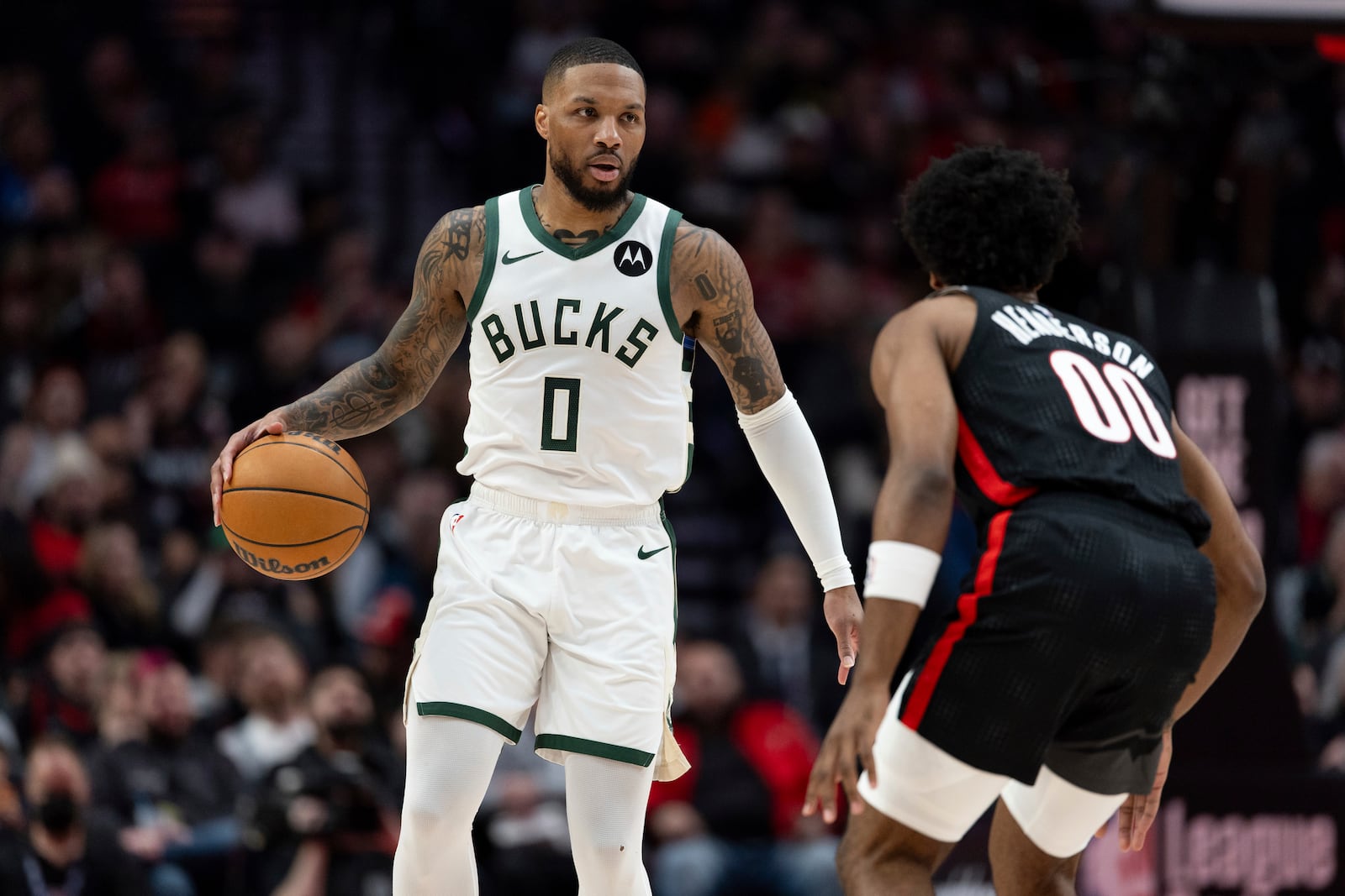 Milwaukee Bucks guard Damian Lillard, left, dribbles the ball against Portland Trail Blazers guard Scoot Henderson during the first half of an NBA basketball game, Tuesday, Jan. 28, 2025, in Portland, Ore. (AP Photo/Howard Lao)