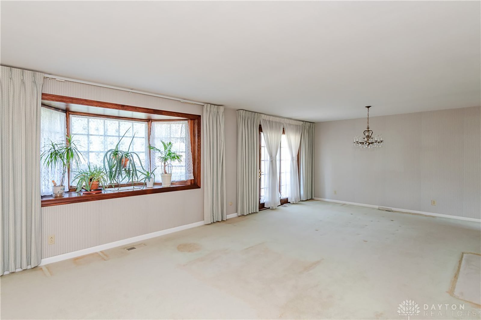 The living room/dining room combination features neutral carpeting and a newer bay window. Sliding glass doors lead to the rear patio.