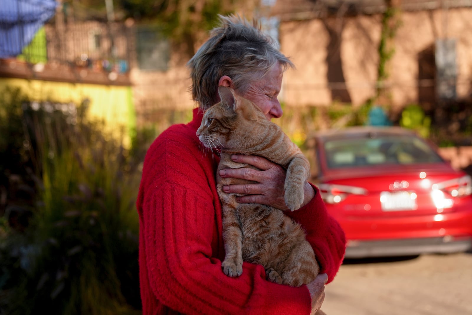 Denise Johnson, whose home is one of the few that survived the Eaton Fire in her neighborhood in Altadena, Calif., holds her cat Ramsey as she and her two children hunker down without power to care for their pets and protect the home Tuesday, Jan. 14, 2025. (AP Photo/Jae C. Hong)