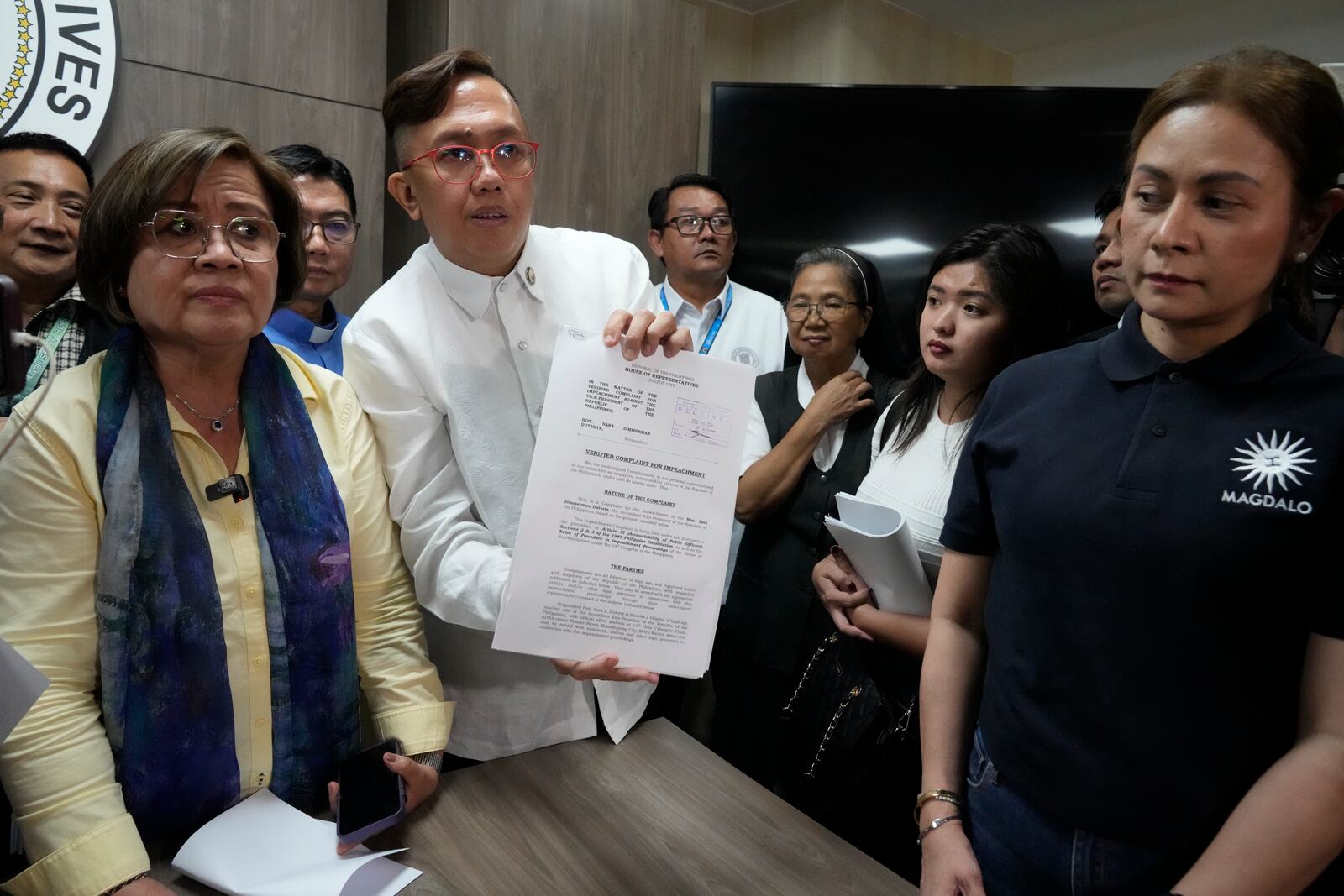 Akbayan Partylist representative Perci Cendana, center, shows a received copy of an impeachment complaint they filed Monday Dec. 2, 2024 against Philippine Vice President Sara Duterte by several prominent opponents and activists, including former Senator Leila de Lima, left, at the House of Representatives in Quezon City, Philippines. (AP Photo/Aaron Favila)