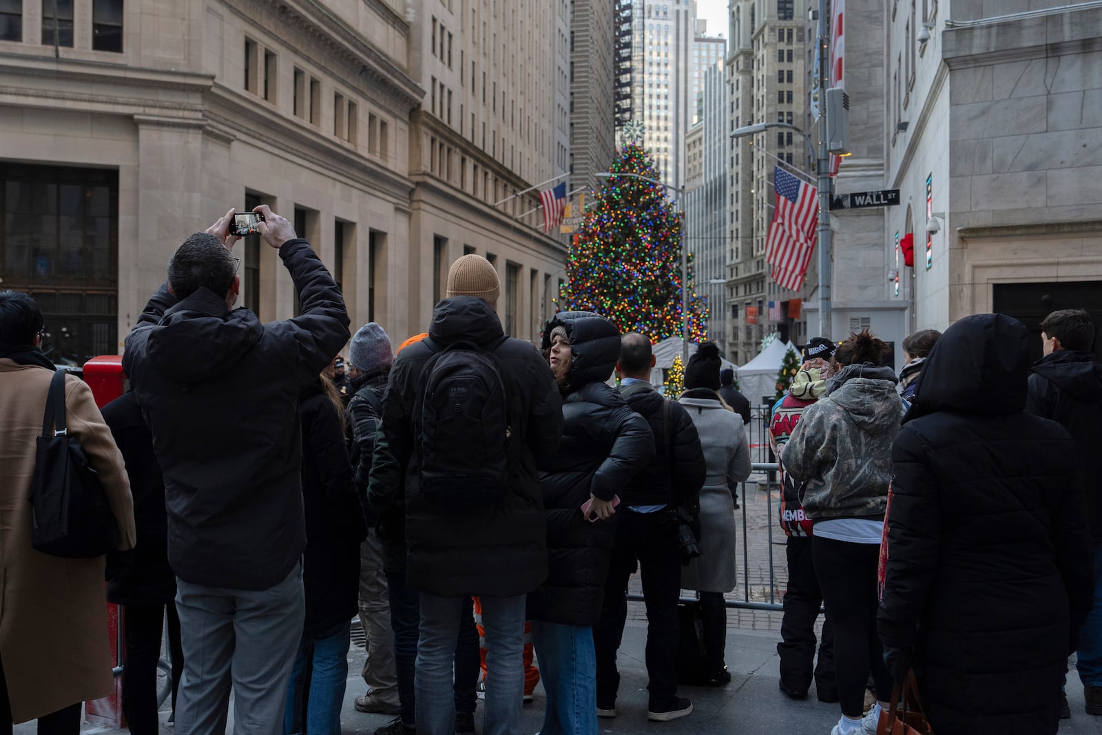 People stand outside the New York Stock Exchange, Thursday, Dec. 12, 2024, in New York. (AP Photo/Julia Demaree Nikhinson)