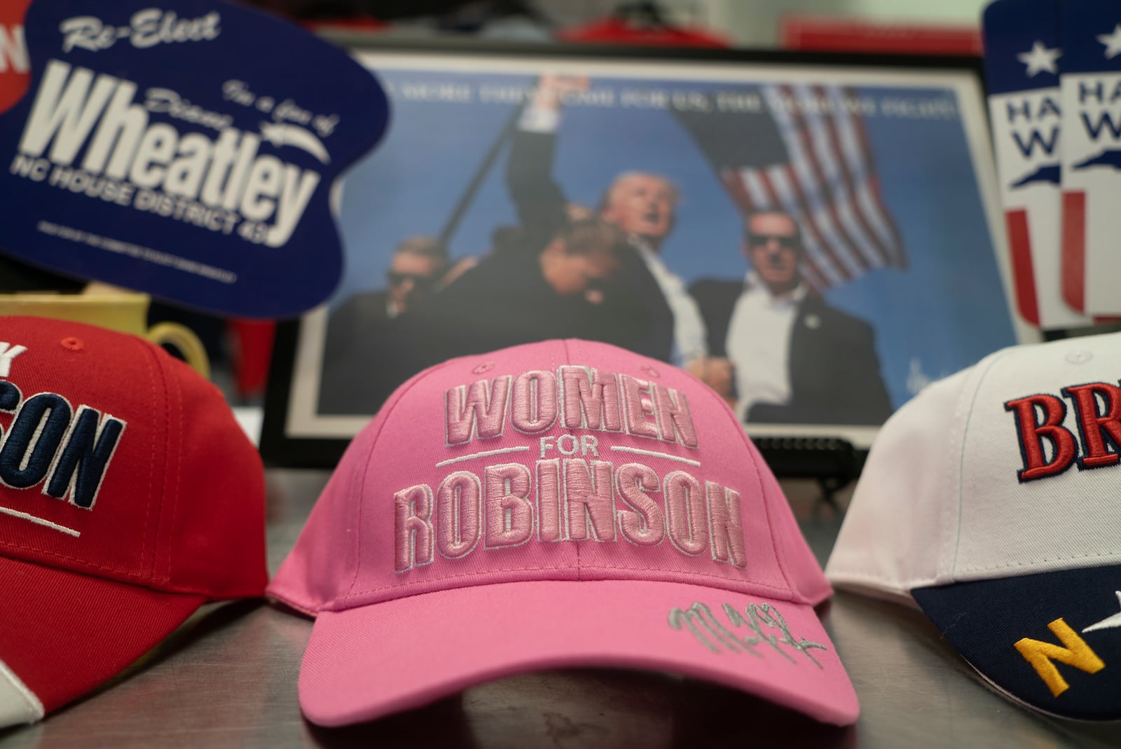 A "Women for Robinson" hat sits in front of a photo of former President Donald Trump at a resource center for Republican candidates in Fayetteville, N.C., on Tuesday, Oct. 1, 2024. Mark Robinson, the GOP gubernatorial nominee, has drawn attention for controversial statements on abortion. (AP Photo/Allen G. Breed)