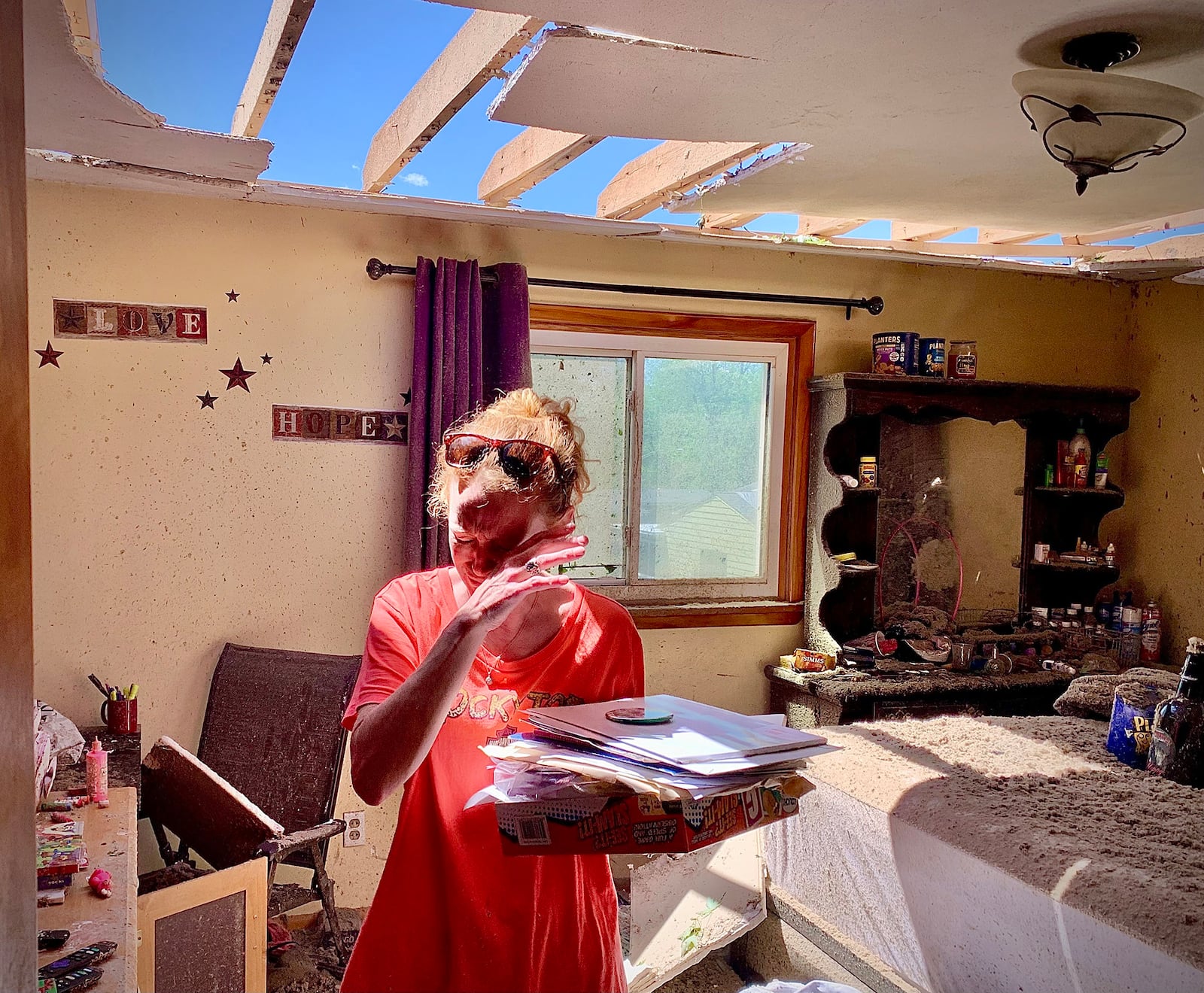 Greenville, Ohio, resident Brenda Pollitt wipes the tears from her eyes as she removes important papers from her bedroom, Wednesday, May 8, 2024. Pollitt and her children were home at the time of the strong storm that hit Tuesday evening, May 7. She and her family ran downstairs and were all safe. 