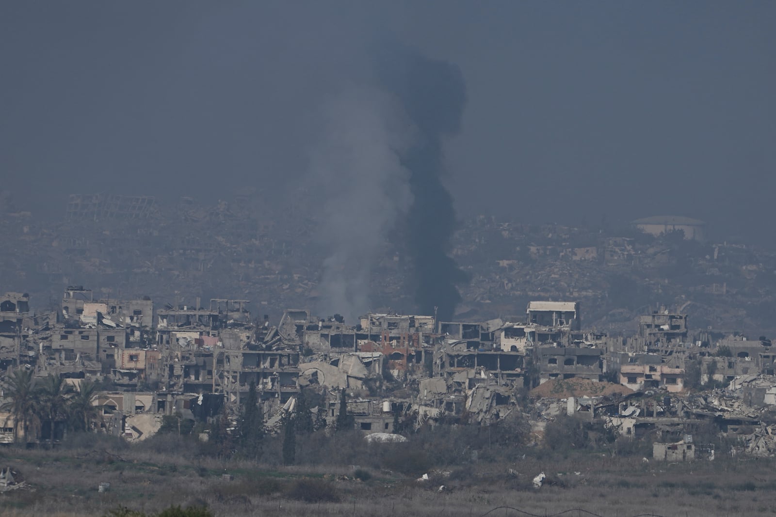 Smoke rises behind destroyed buildings by Israeli bombardments as seen inside the Gaza Strip from southern Israel, Thursday, Jan. 16, 2025. (AP Photo/Tsafrir Abayov)