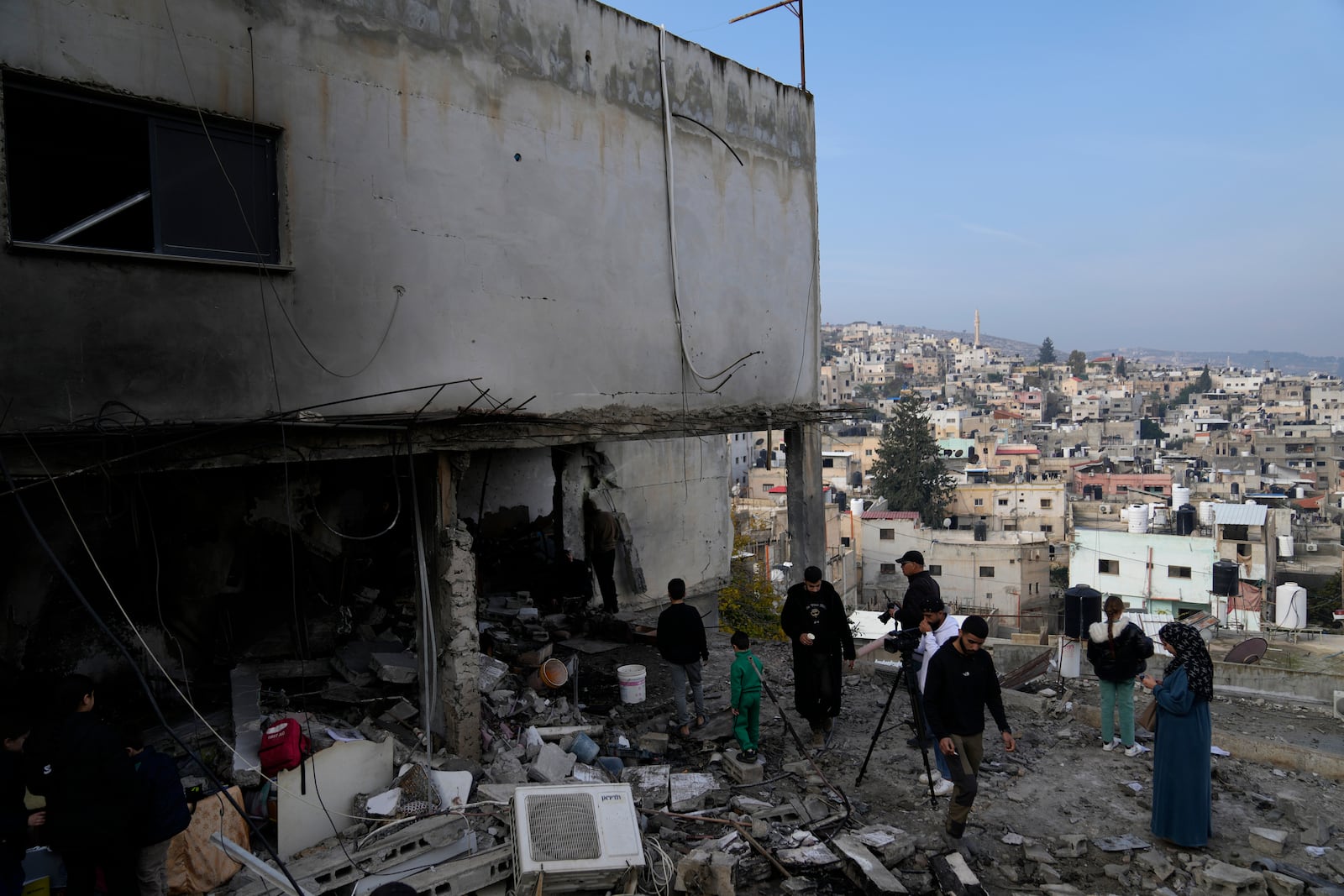 Residents inspect the location of the Israeli airstrike that killed six Palestinians on Wednesday, in the West Bank refugee camp of Jenin, Thursday, Jan. 16, 2025. (AP Photo/Nasser Nasser)