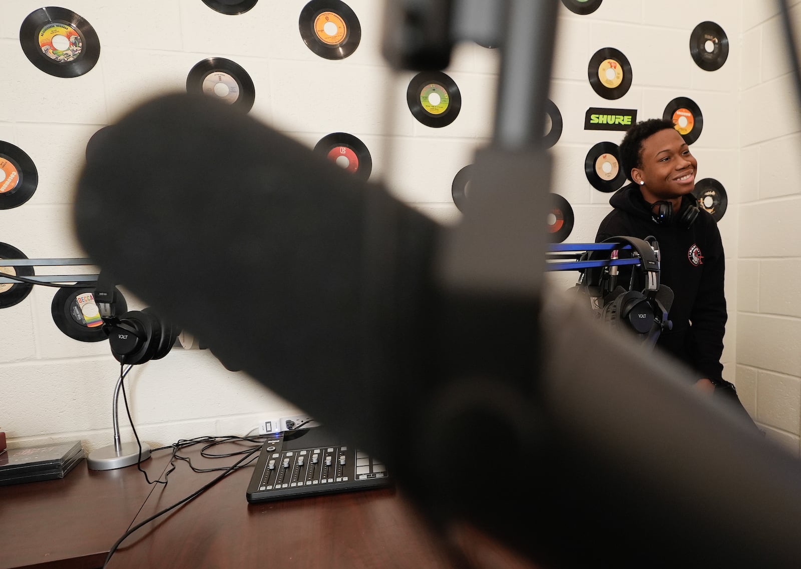 D. M. Therrell High School student Ja'Marion Hulin, 17, who runs the school's record company, Panther Records, laughs with another student in the school's podcast recording room Monday, Jan. 27, 2025, in Atlanta. (AP Photo/Brynn Anderson)