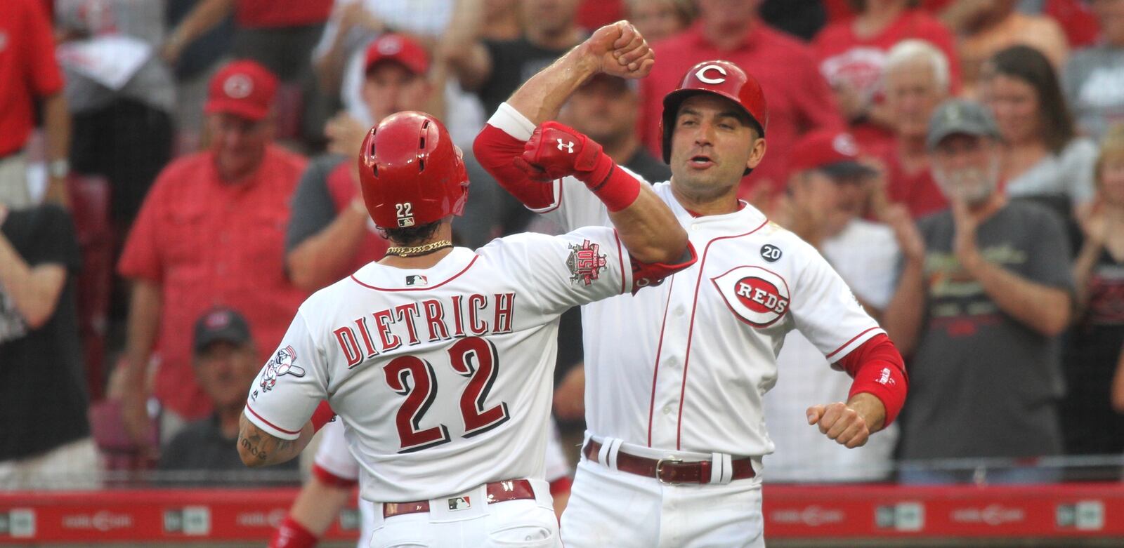 The Reds’ Derek Dietrich, left, crosses home plate and celebrates with Joey Votto after hitting a two-run home run against the Astros on Tuesday, June 18, 2019, at Great American Ball Park in Cincinnati. David Jablonski/Staff